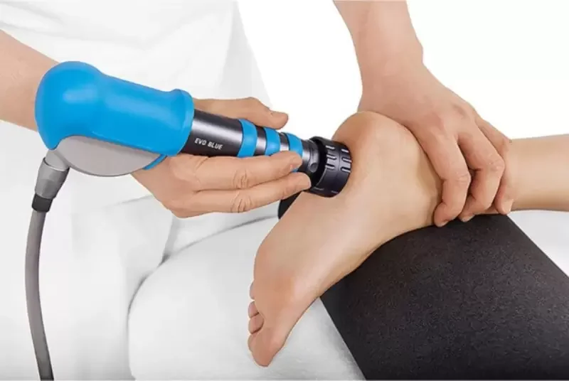 A person receiving physical therapy, with a therapist using a handheld electrical stimulation device on their ankle.