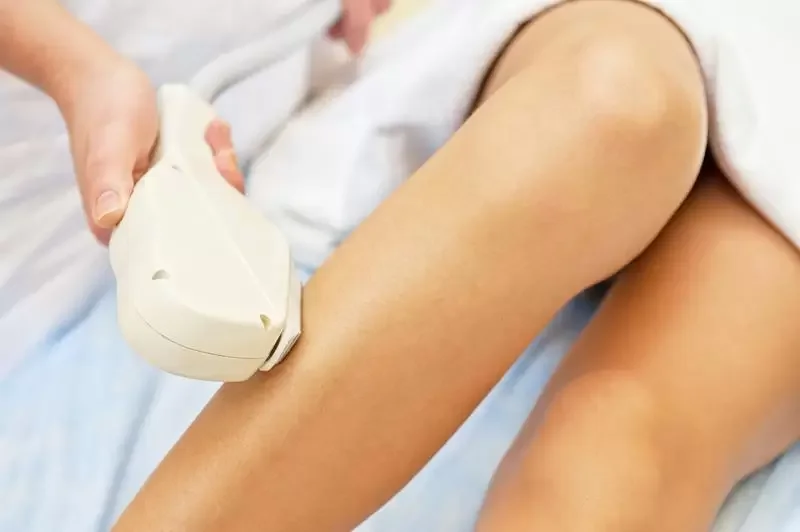 Person receiving an ultrasound scan on their thigh in a medical setting.