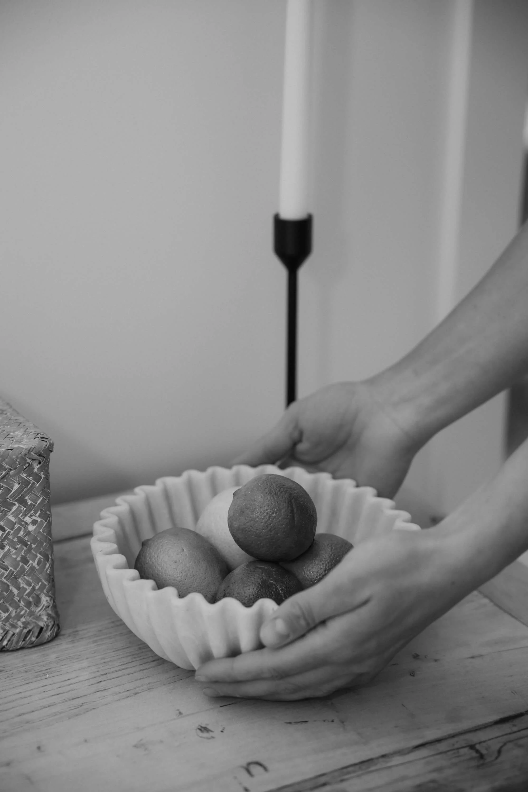 A person holding a fruit bowl and candle in the background.