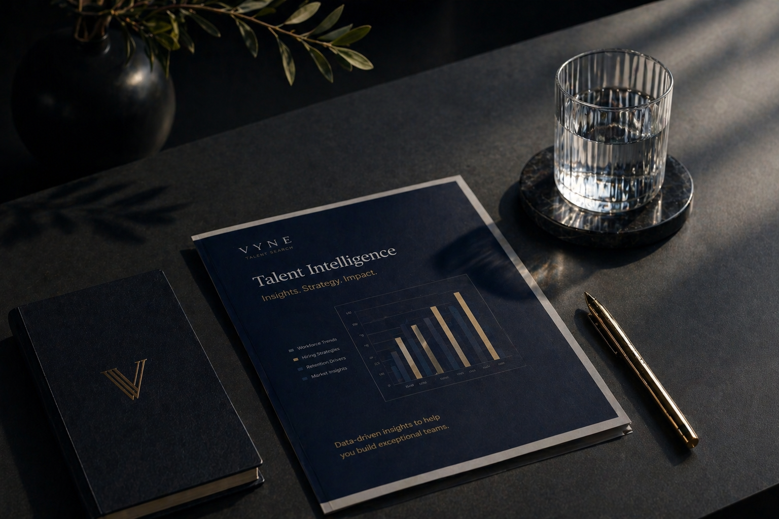 Desk with a notebook, a document titled 'Talent Intelligence,' a pen, a glass of water on a coaster, a plant in a black vase, and sunlight streaming across the surface.