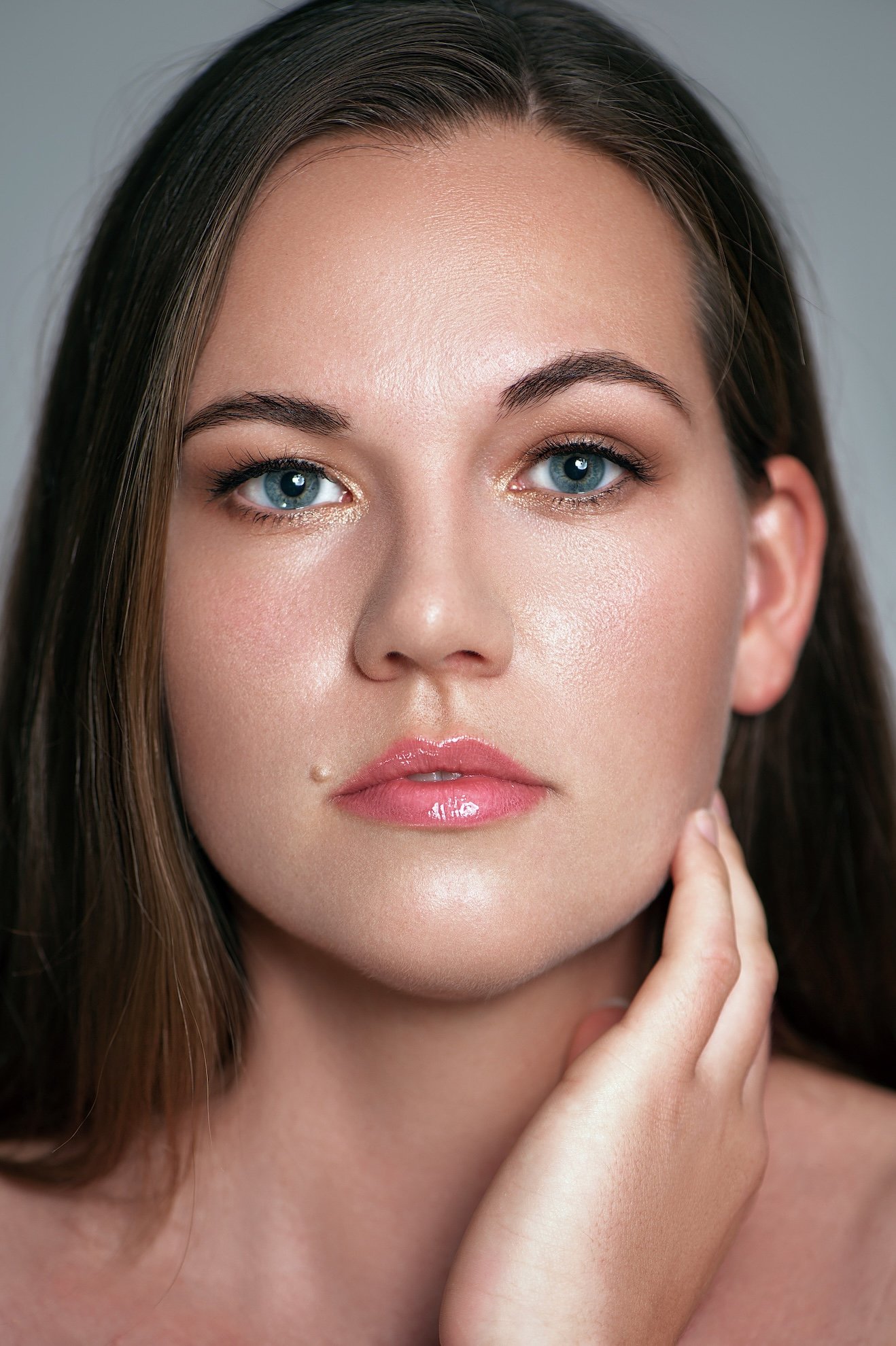 Nahaufnahme einer Frau mit blauen Augen, braunen Haaren, natürlicher Make-up, leicht glänzenden Lippen.