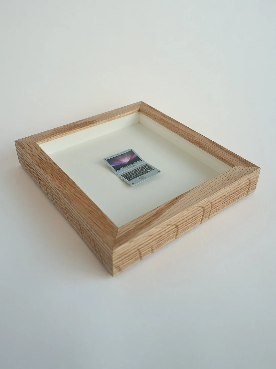 A miniature MacBook, a memento from a magician, kept safe in an oak box frame, behind AR70 low-reflection glass. 

💻💻💻