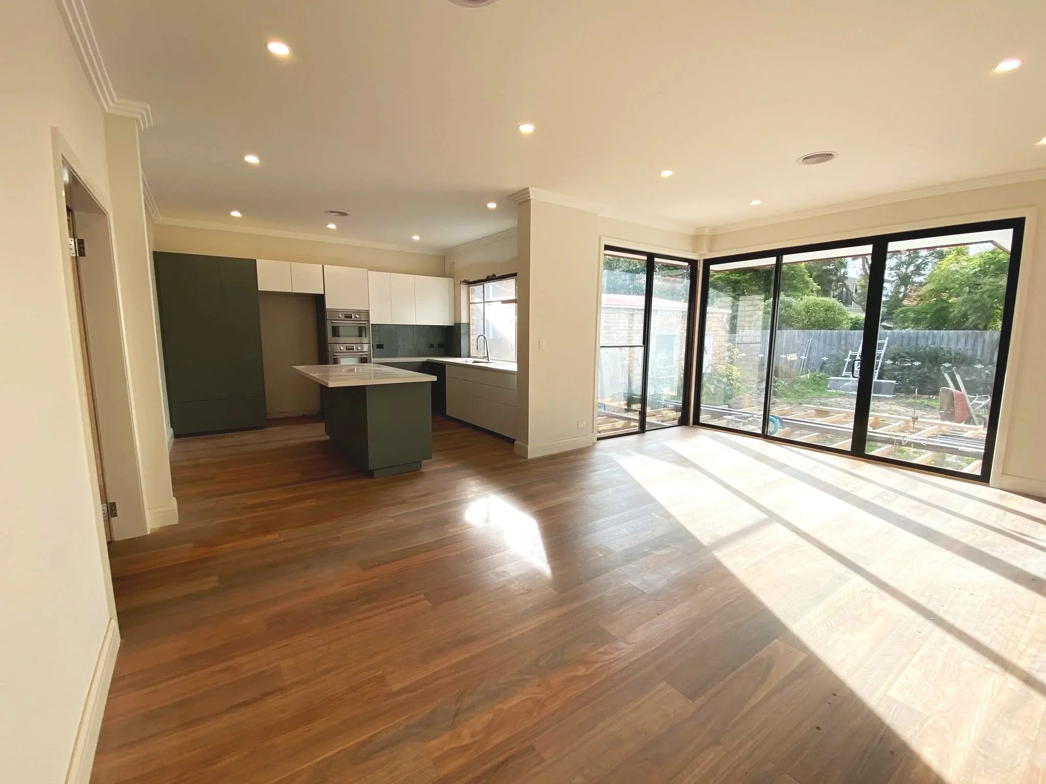 A modern kitchen and dining area with large sliding glass doors leading to a backyard with outdoor furniture and trees.