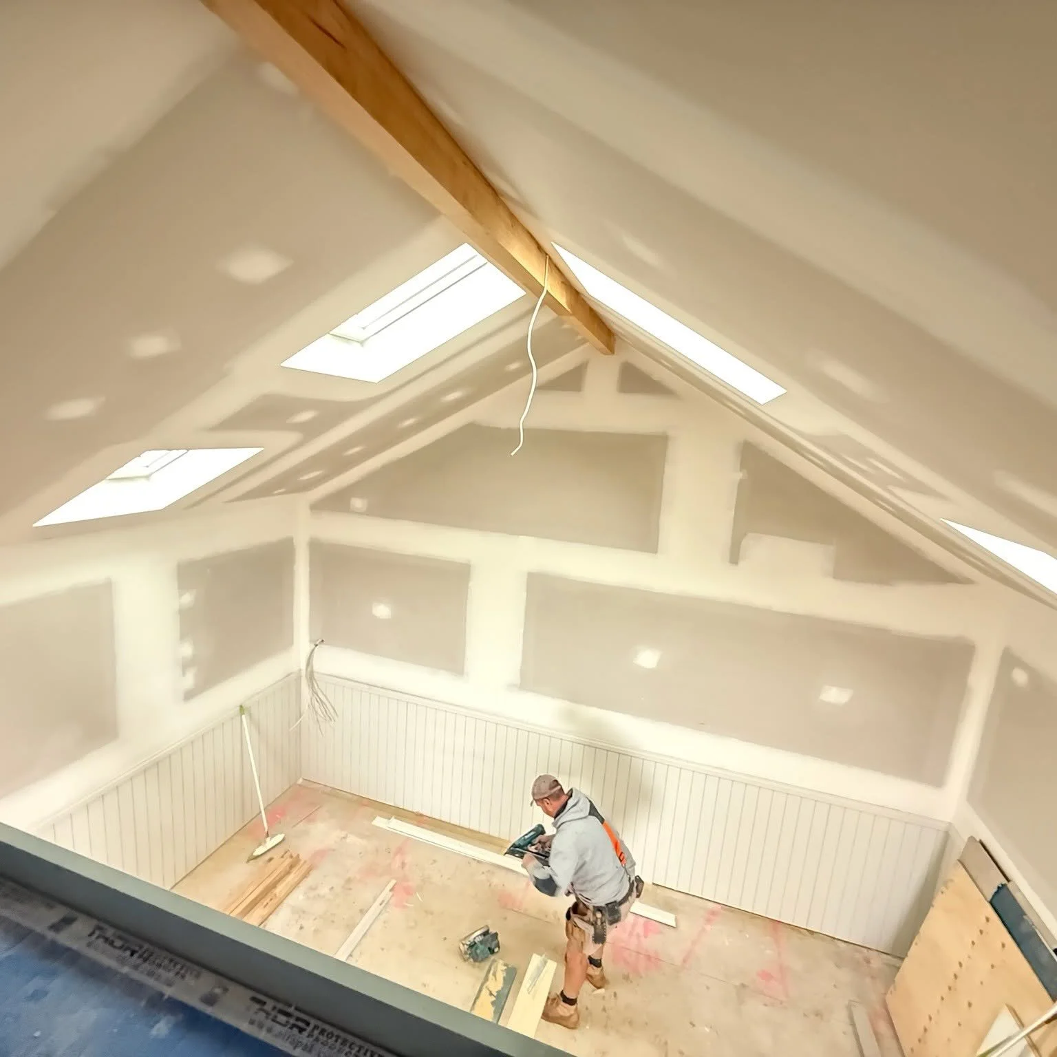 Carpenter working under the skylit raked ceiling, beach boatshed rebuild