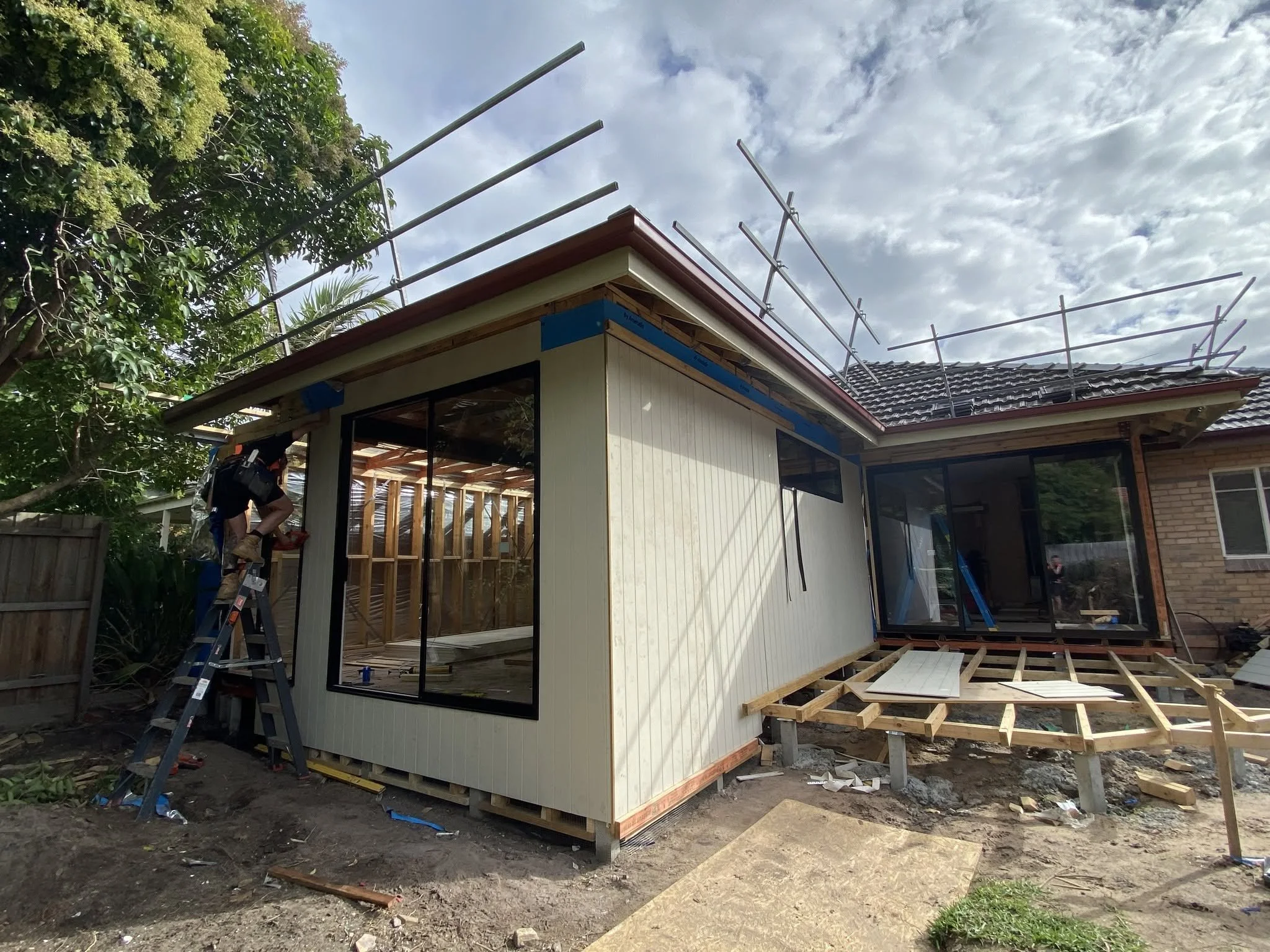 New extension clad and windows installed, with the deck subfloor framed and scaffolding still on the roof line