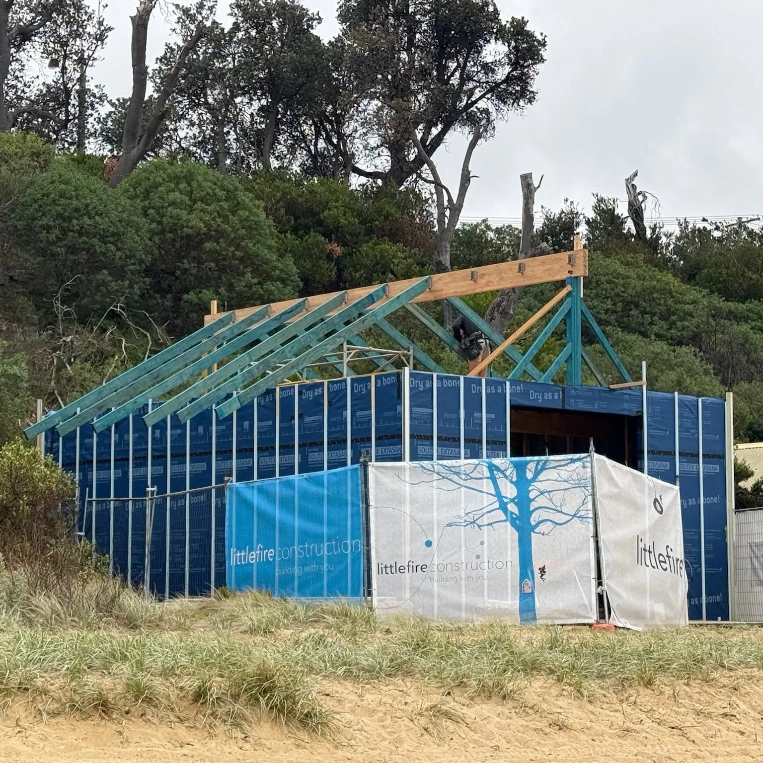 Roof trusses behind Littlefire site fencing, beach boatshed rebuild