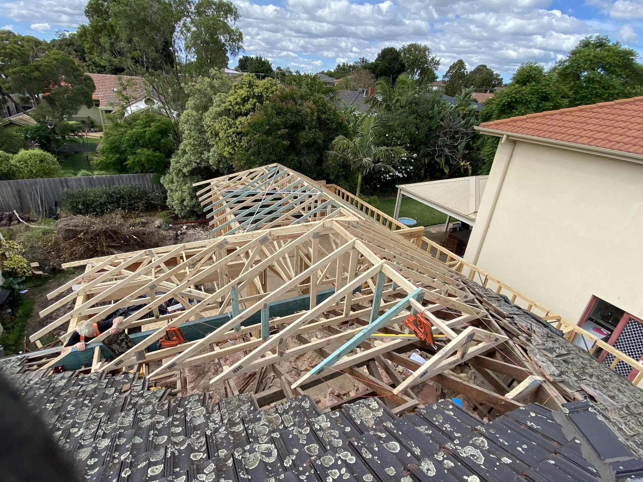 New pitched roof trusses being installed over the existing tiled roof of the McKinnon home