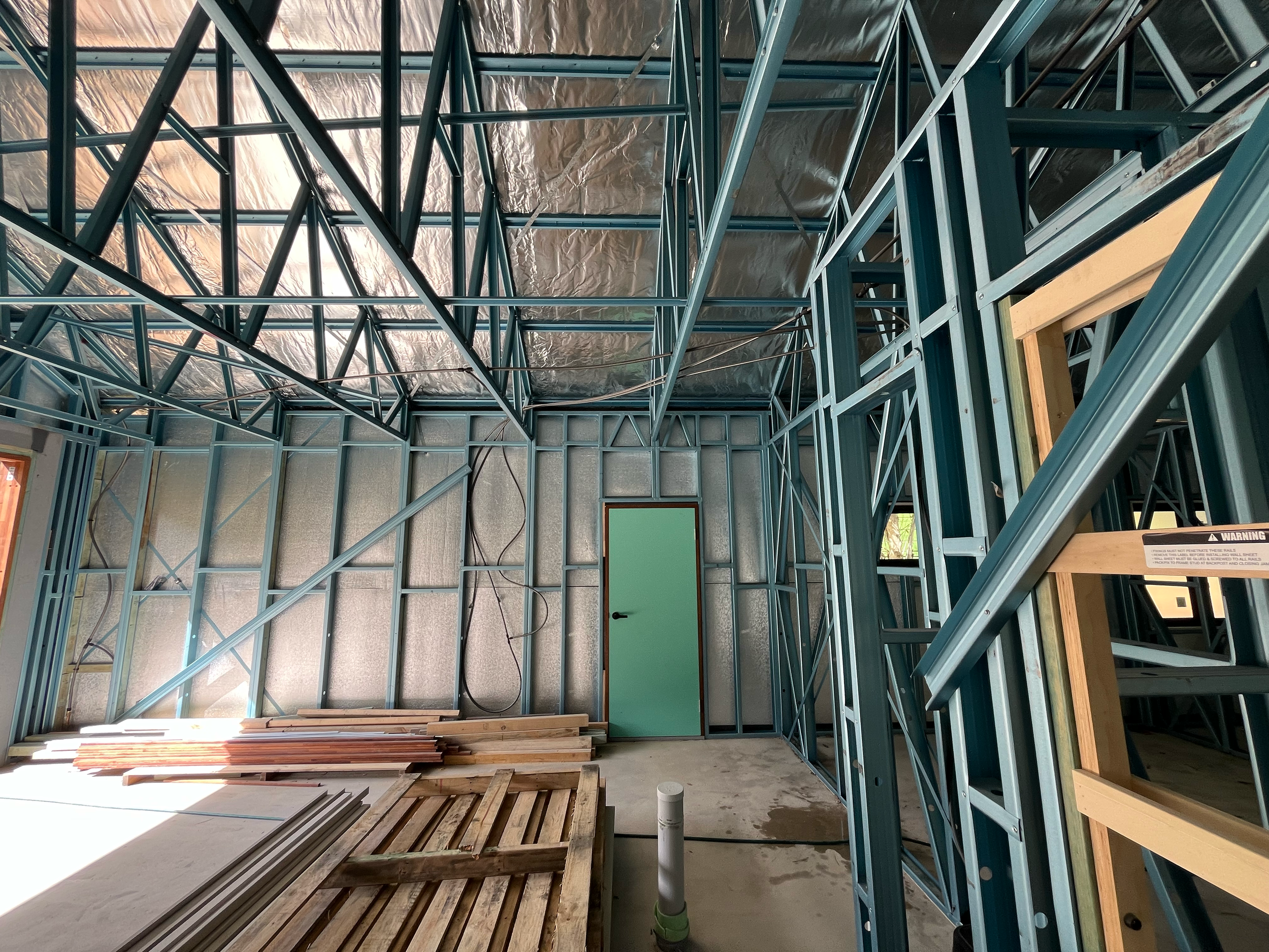 Inside the steel frame of the Alpine kit home, with roof sarking installed under the raked trusses