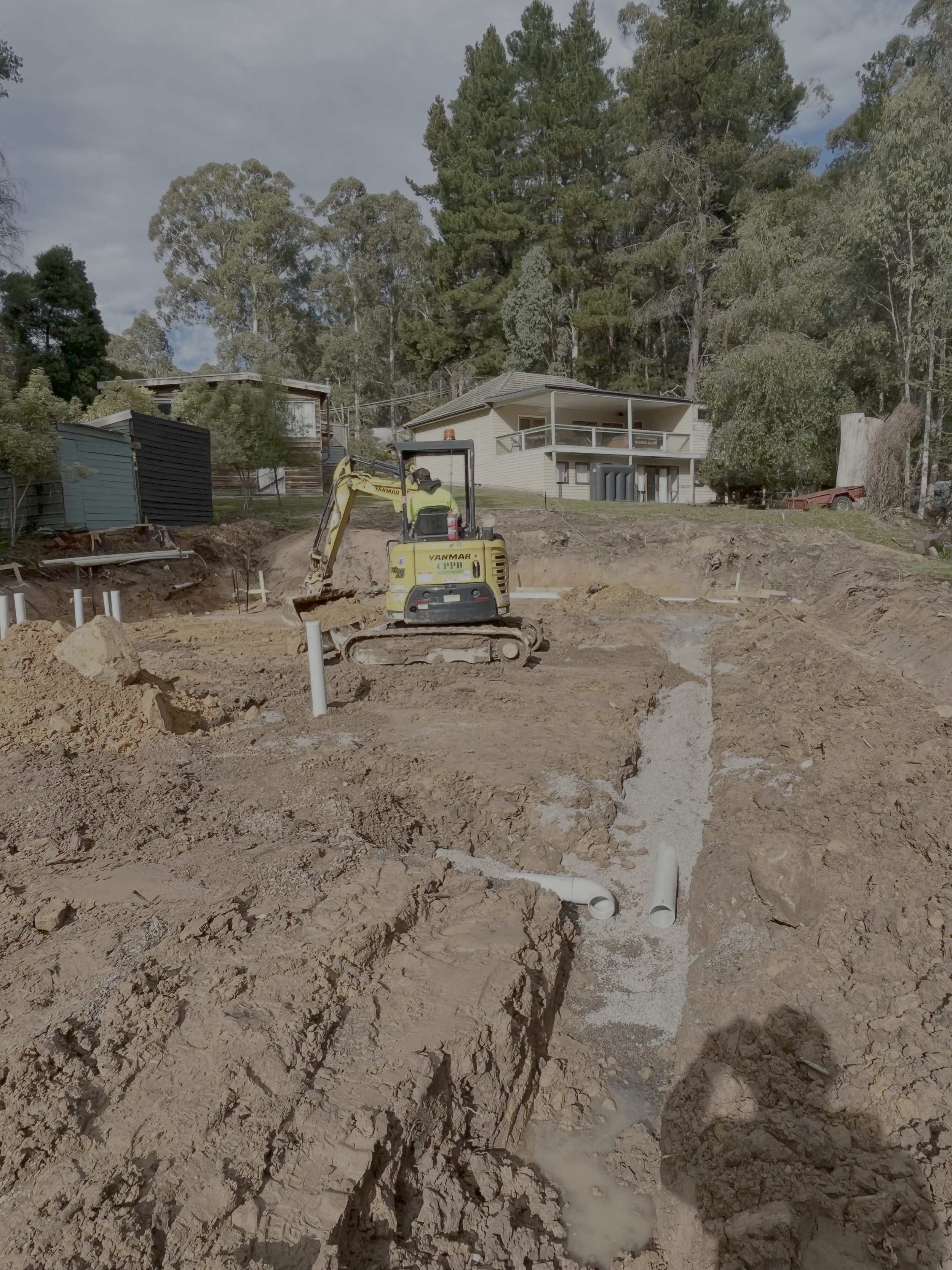 Site preparation near Mansfield, with an excavator trenching for services and footings
