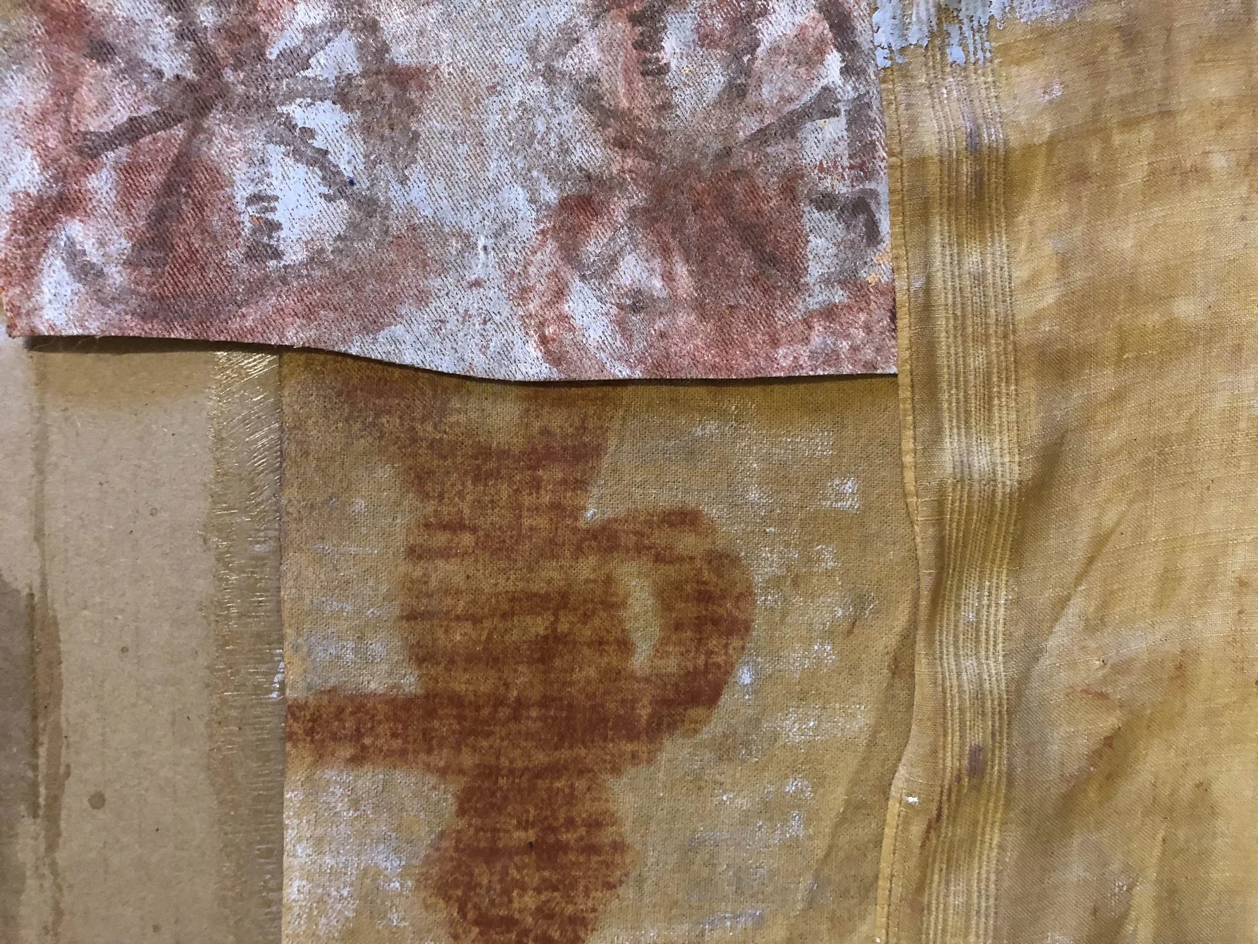 Close-up of textured, colorful woven fabric with overlapping sections in shades of beige, brown, red, and gold.