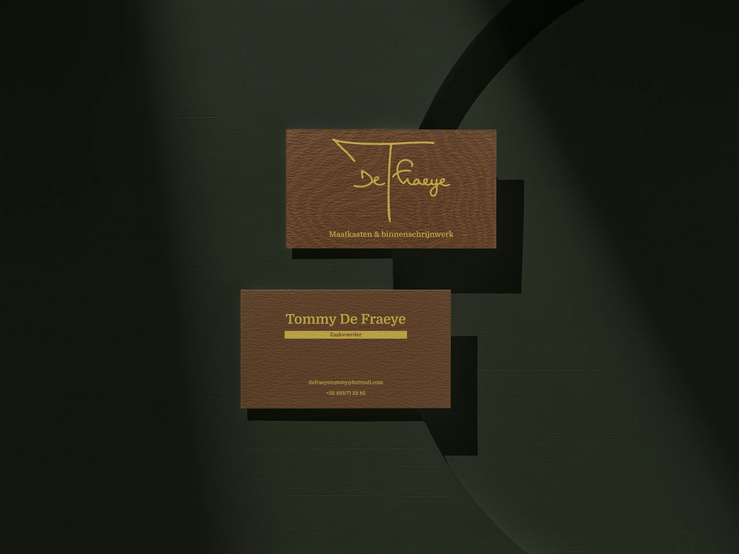 Twee visitekaartjes van een bedrijf genaamd 'De Fraeye' met contactgegevens en een logo, geplaatst op een donkere achtergrond.
