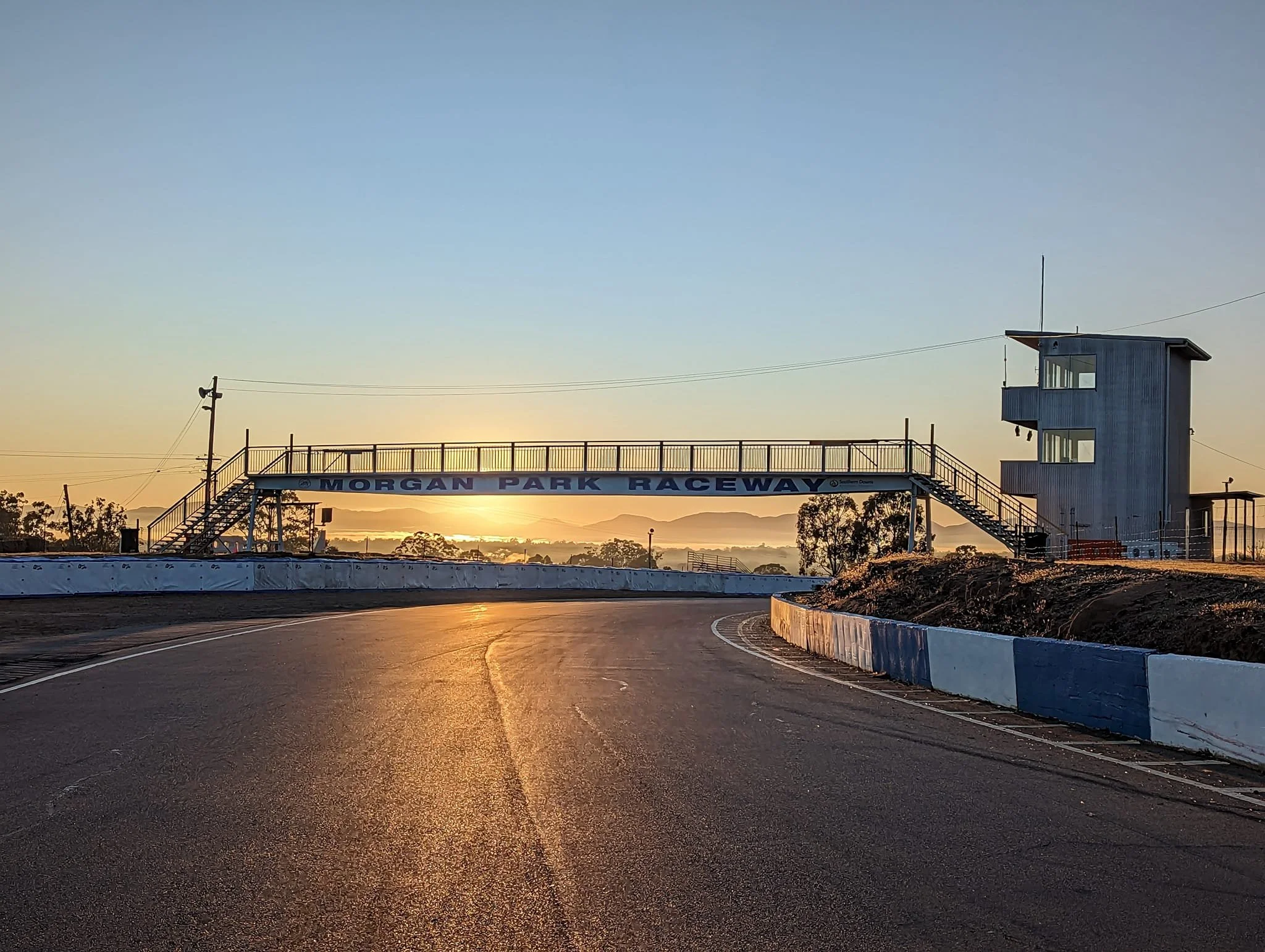 Sunset view of Morgan Park Raceway with a clear sky, empty track, and a modern control tower on the right side.