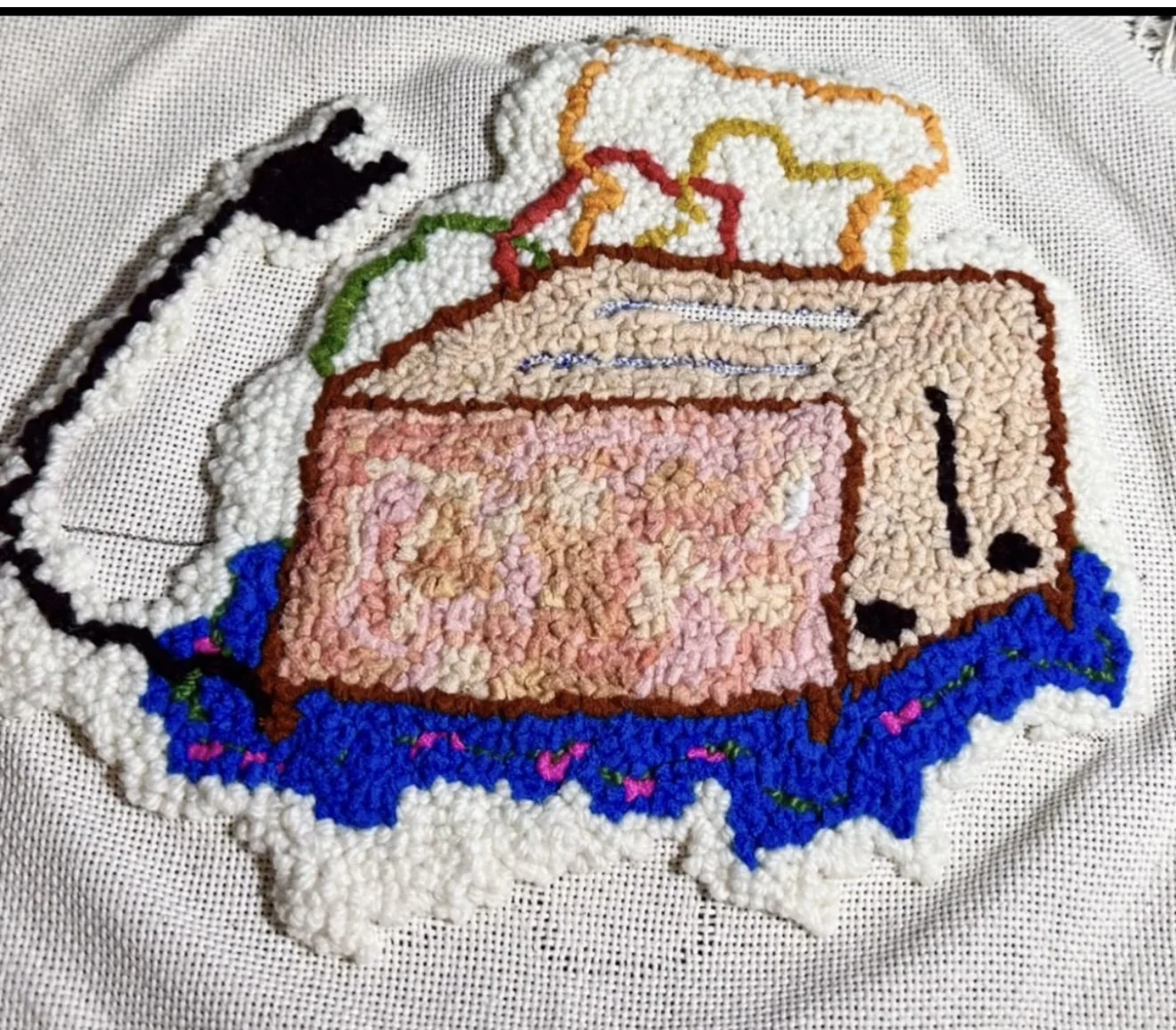 Colorful rug design featuring a vintage toaster with pink, brown, green, black, and blue details on a white fabric background.