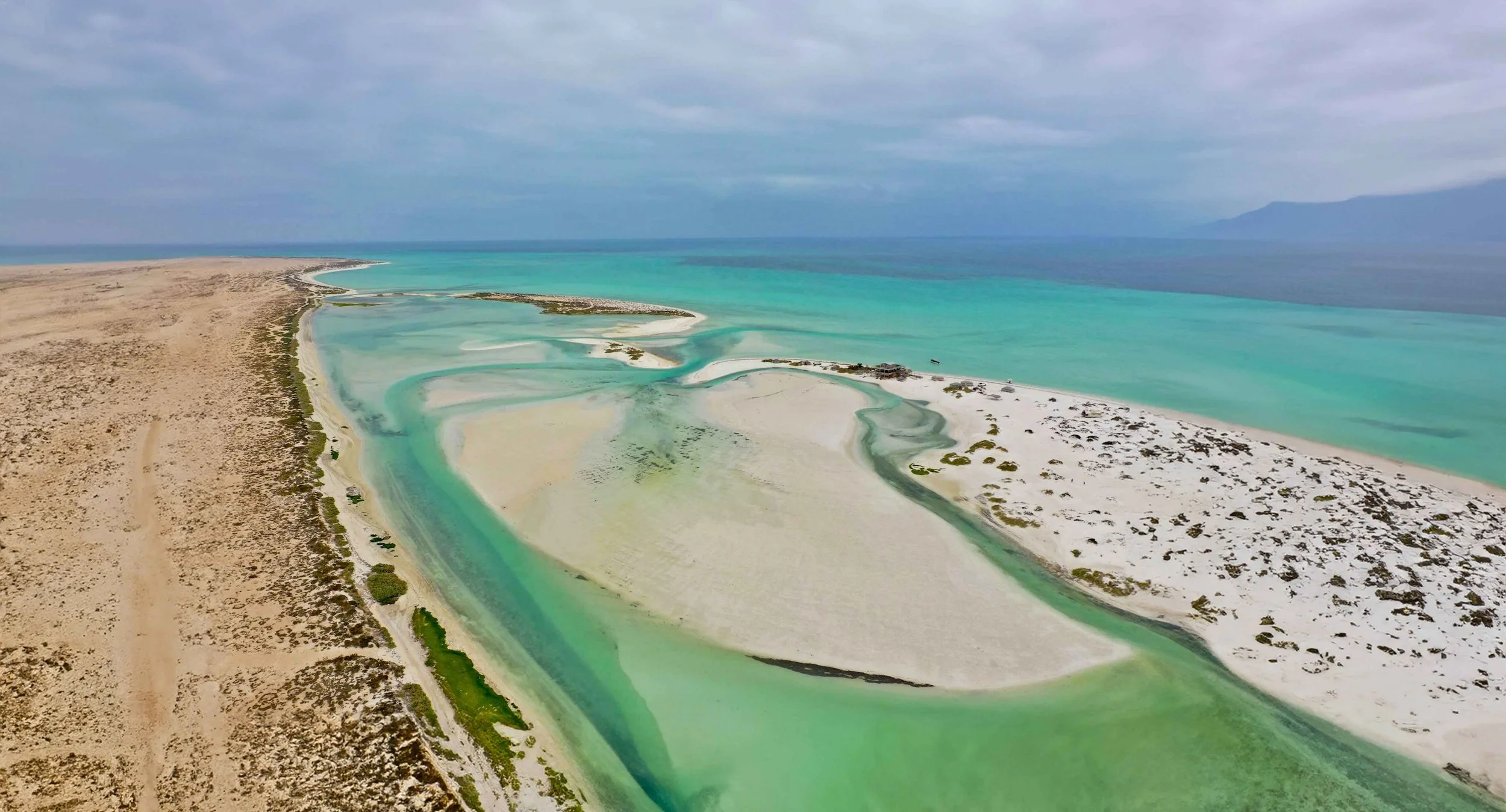 Aerial view of a coastal landscape with sandy beaches, turquoise water, and small islands, possibly a delta or lagoon area with areas of shallow water and land.
