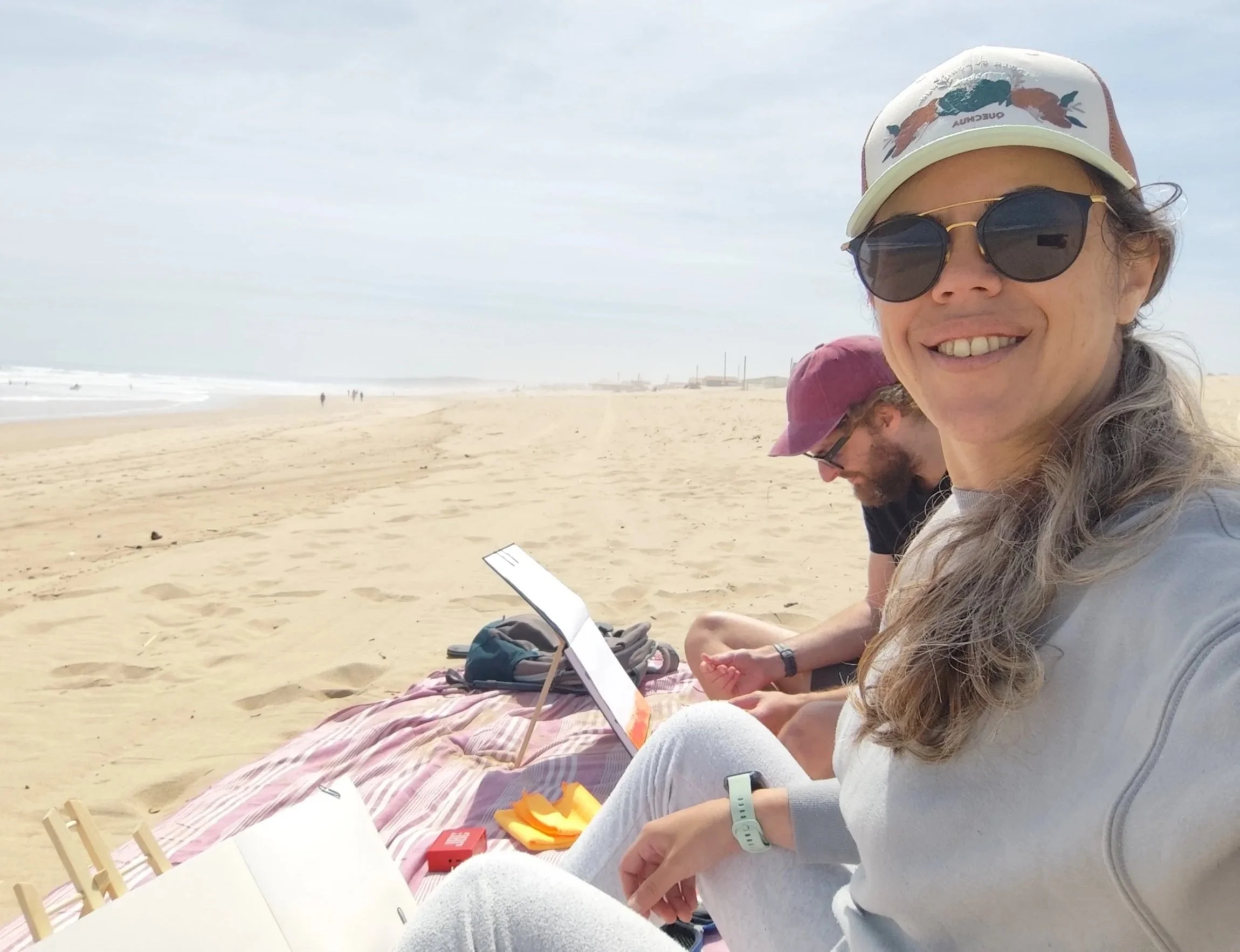 Roei & Chaya Bachar-Hurwitz painting together on the beach, reflecting the creative practice behind Coastline Heron.