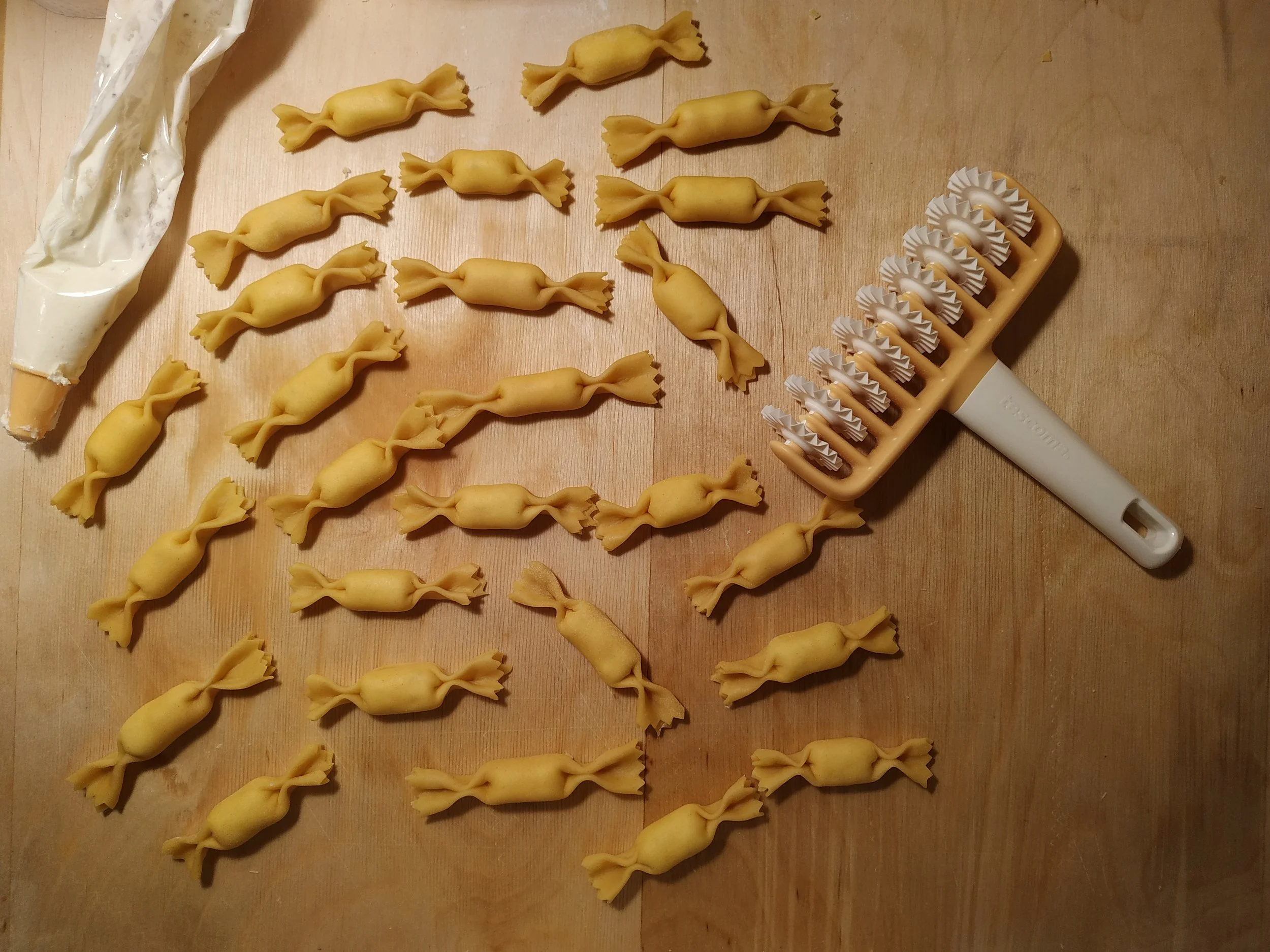 Handmade malloreddus arranged in rows on a wooden surface, with a ridged pasta board nearby.