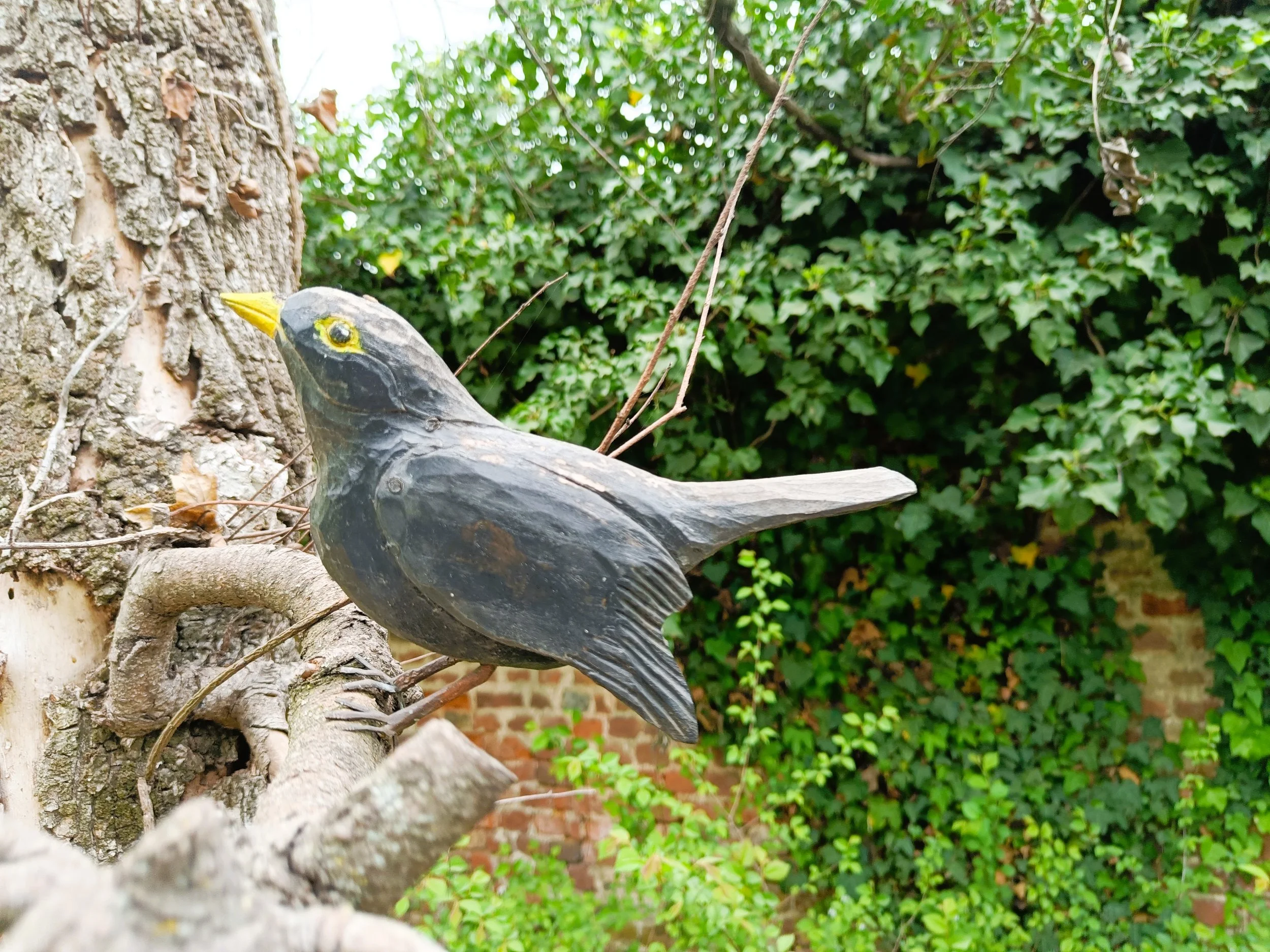 A decorative grey bird, in the garden, suggesting stillness and suspension.