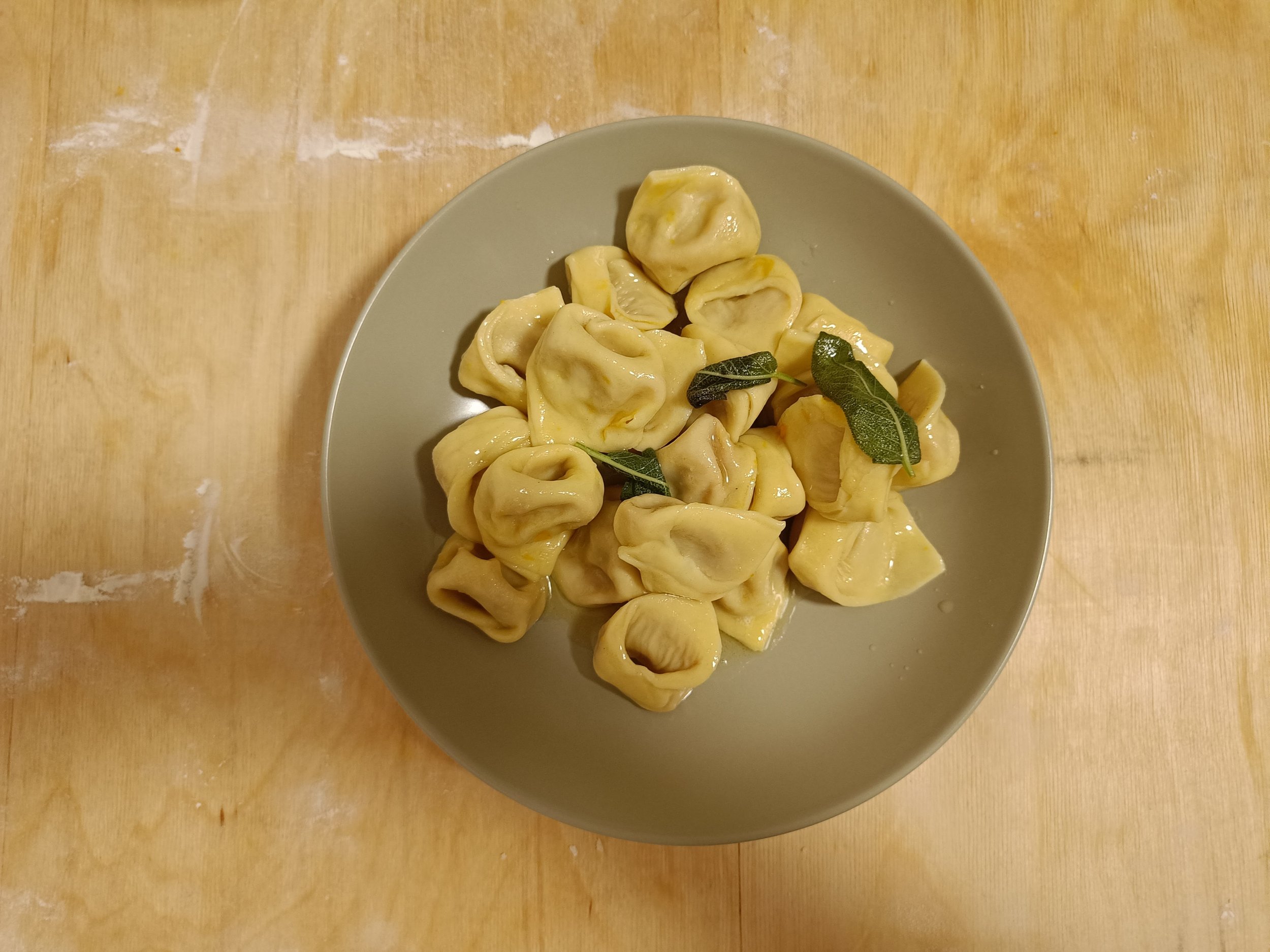Fresh cooked cappelletti served with butter and sage on a plate.