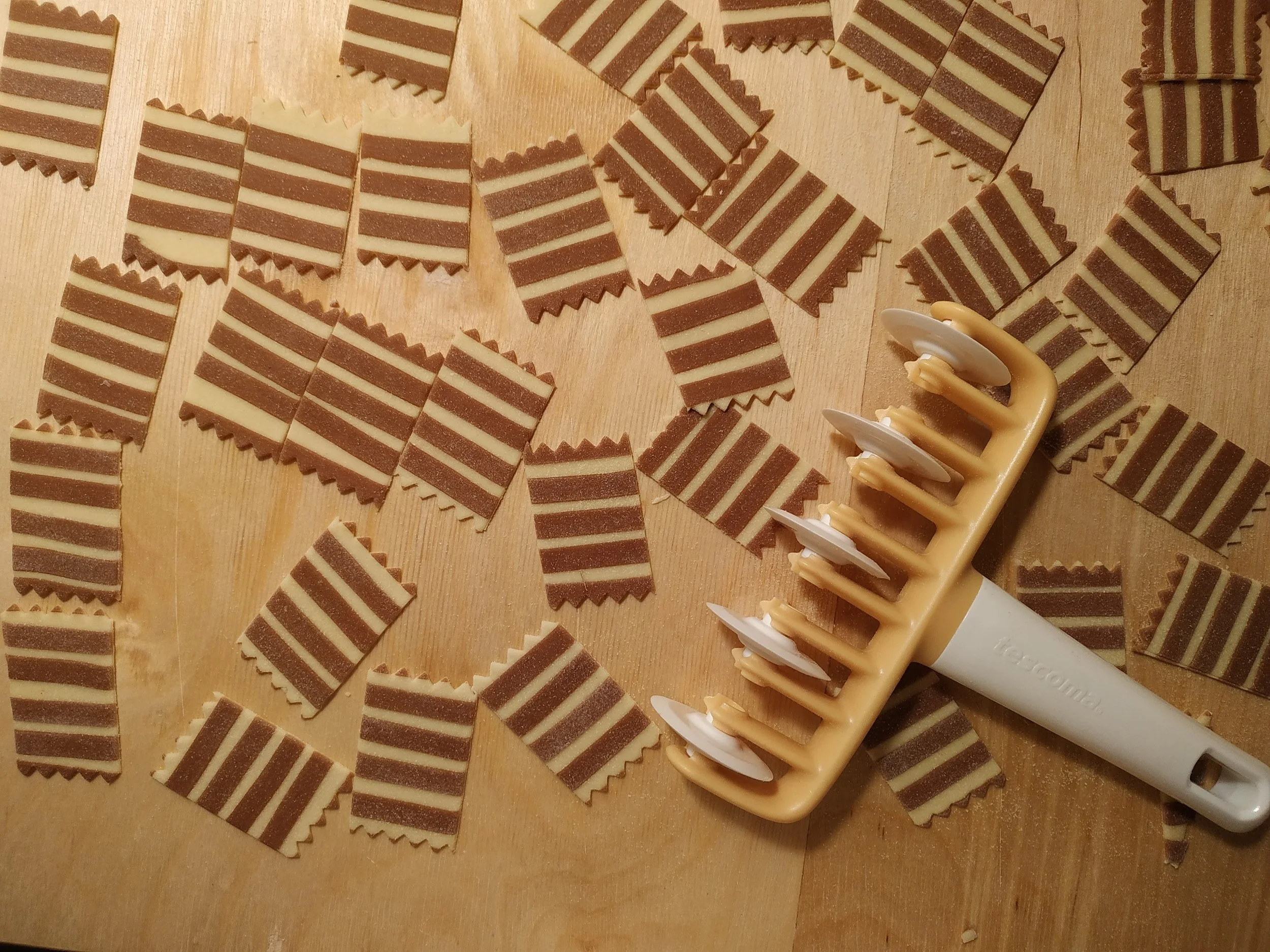 Striped fresh pasta dough made with chocolate, laid out on a wooden surface before being shaped into pasta.