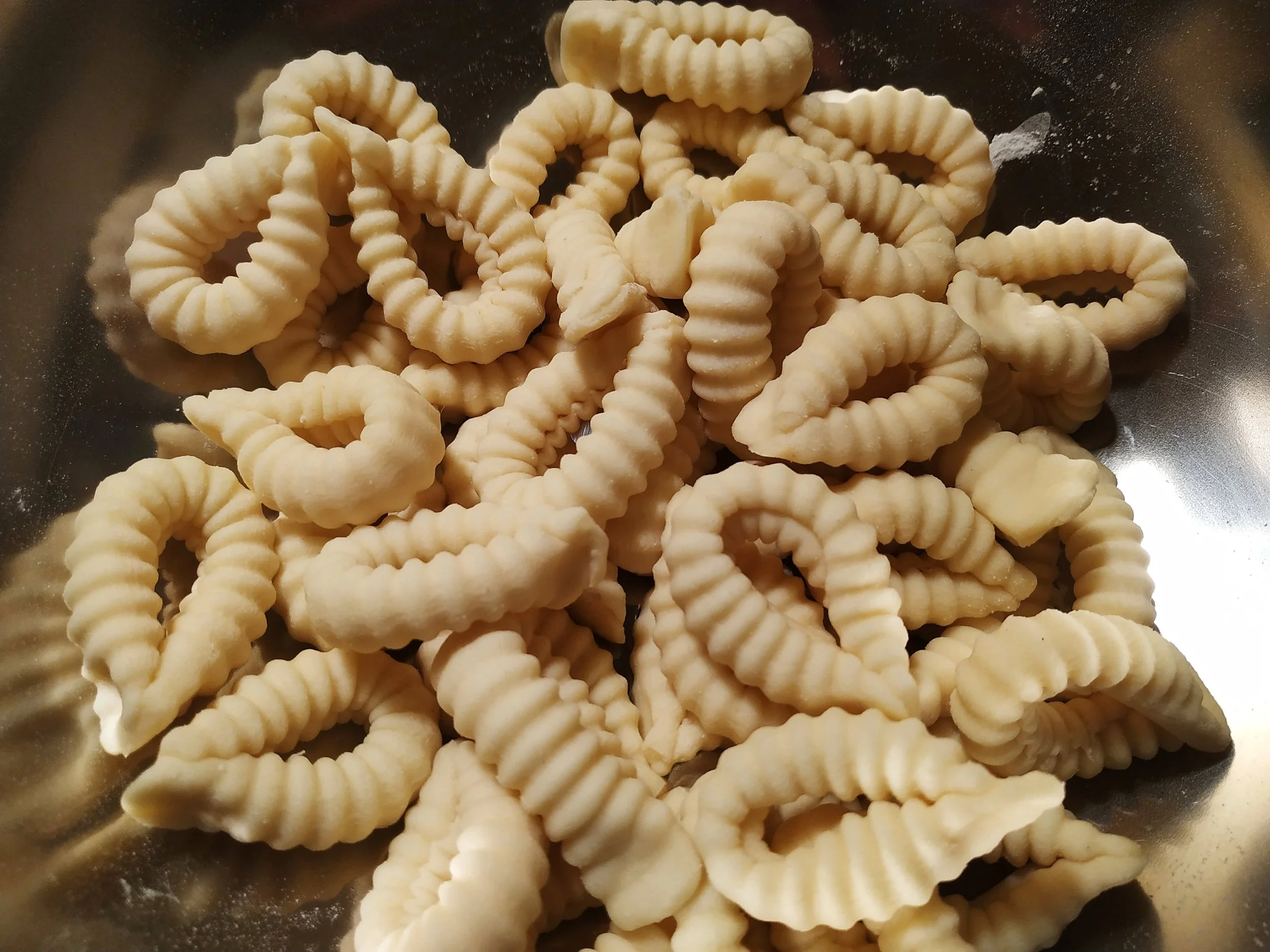Fresh handmade malloreddus, the ridged Sardinian pasta also known as gnocchetti sardi, in a metal bowl.