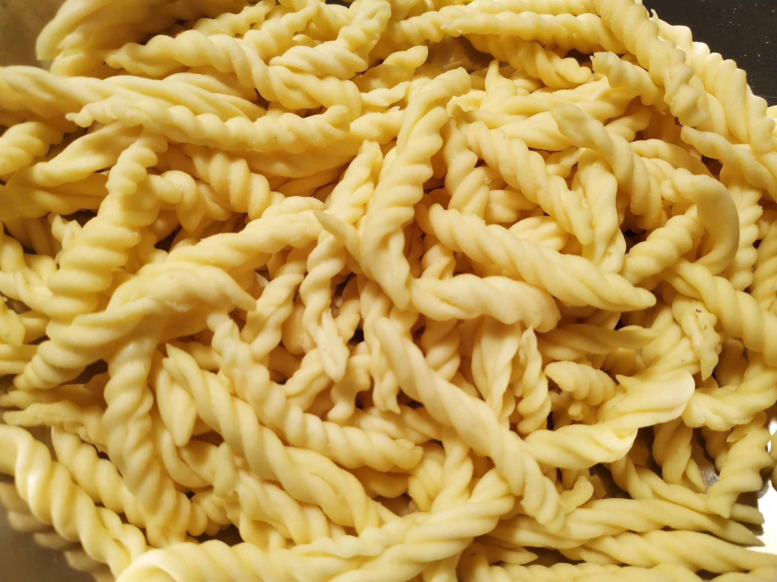 Fresh handmade fusilli on a wooden surface.