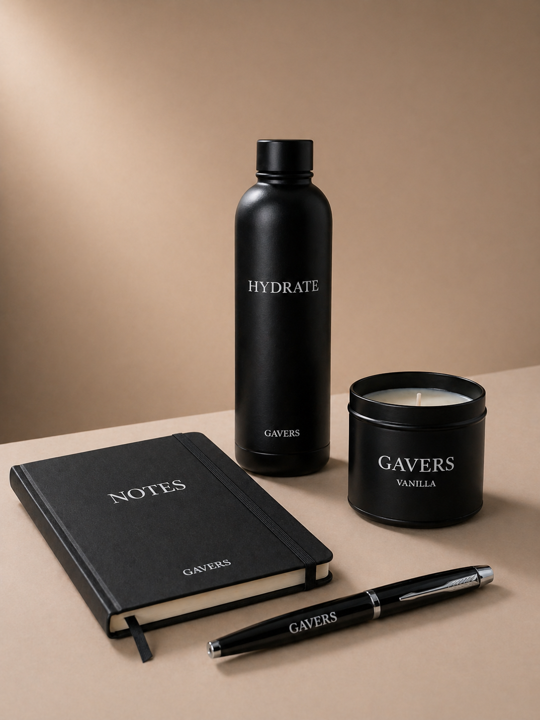 Black Gavers branded thermal water coffee  bottle, vanilla candle, Black A5 notebook, and Black pen on beige surface with plain background.