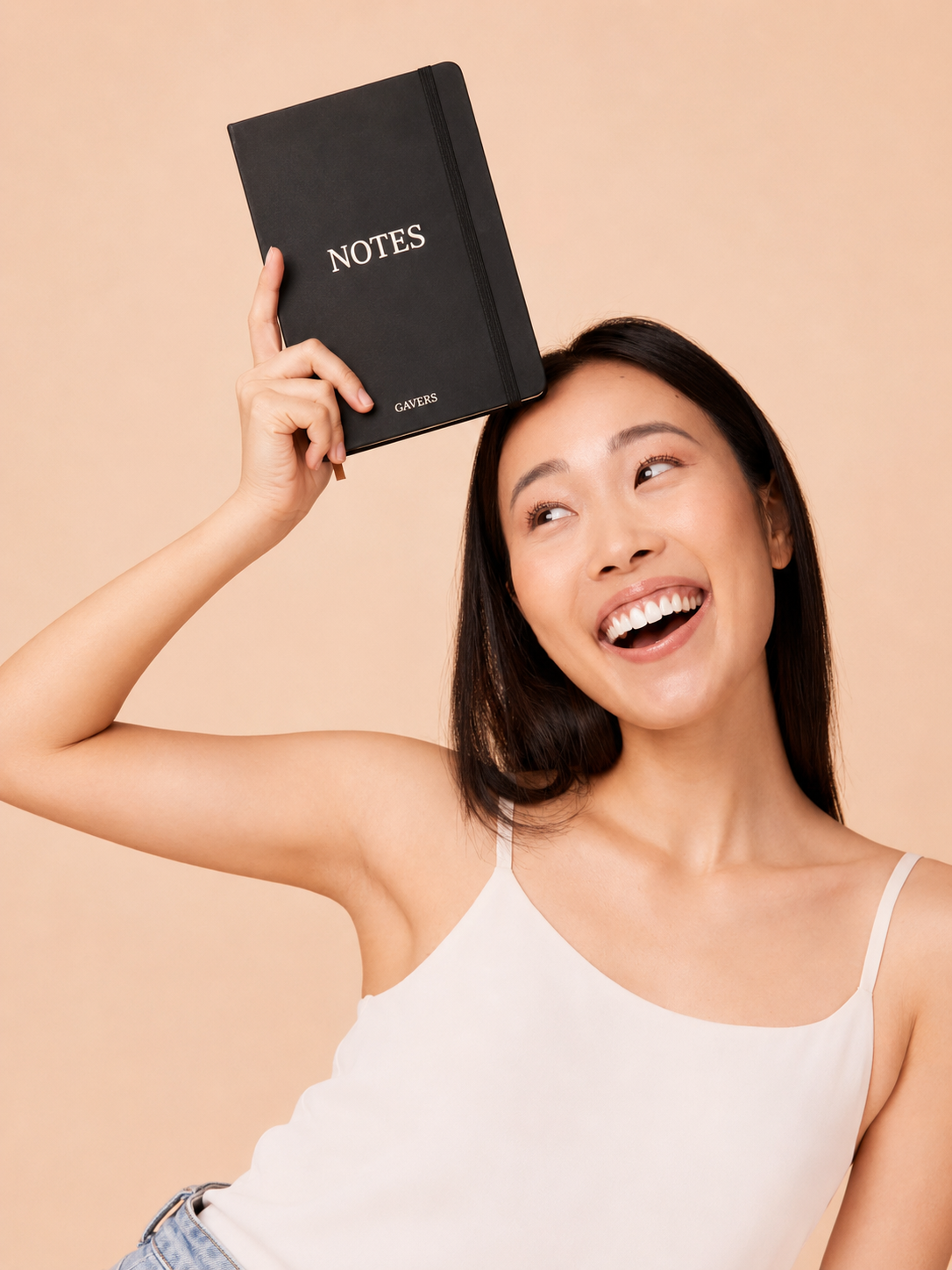 A woman smiling and holding a black notebook labeled "NOTES" and "GIVERS" against a beige background.