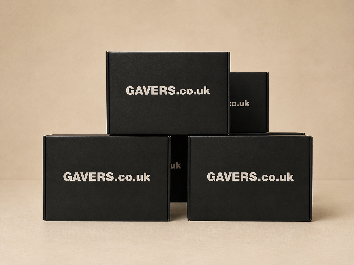 Four black boxes with white text that read "GAVERS.co.uk," arranged in a pyramid on a beige surface against a beige background.