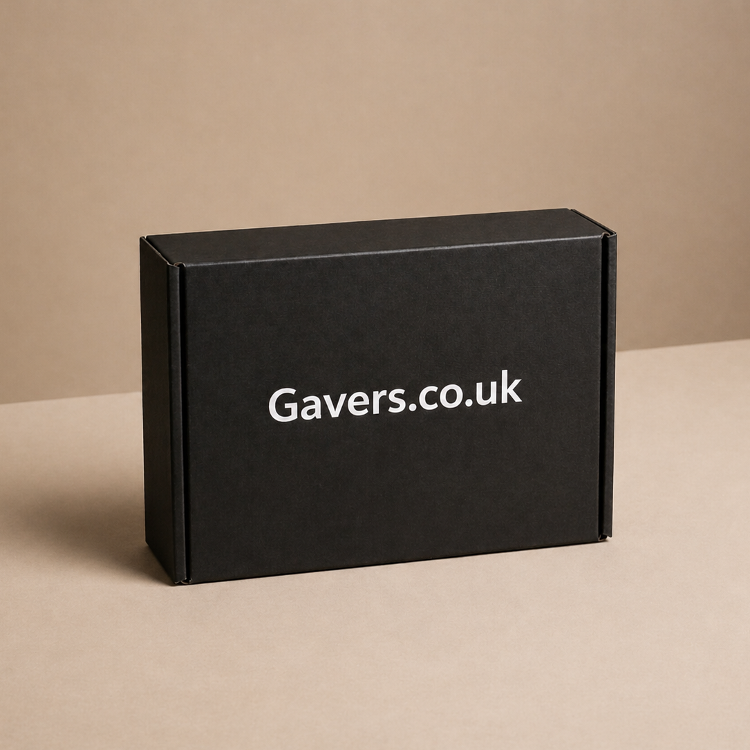 Black box with white text reading Gavers.co.uk on a beige surface with a beige wall background.