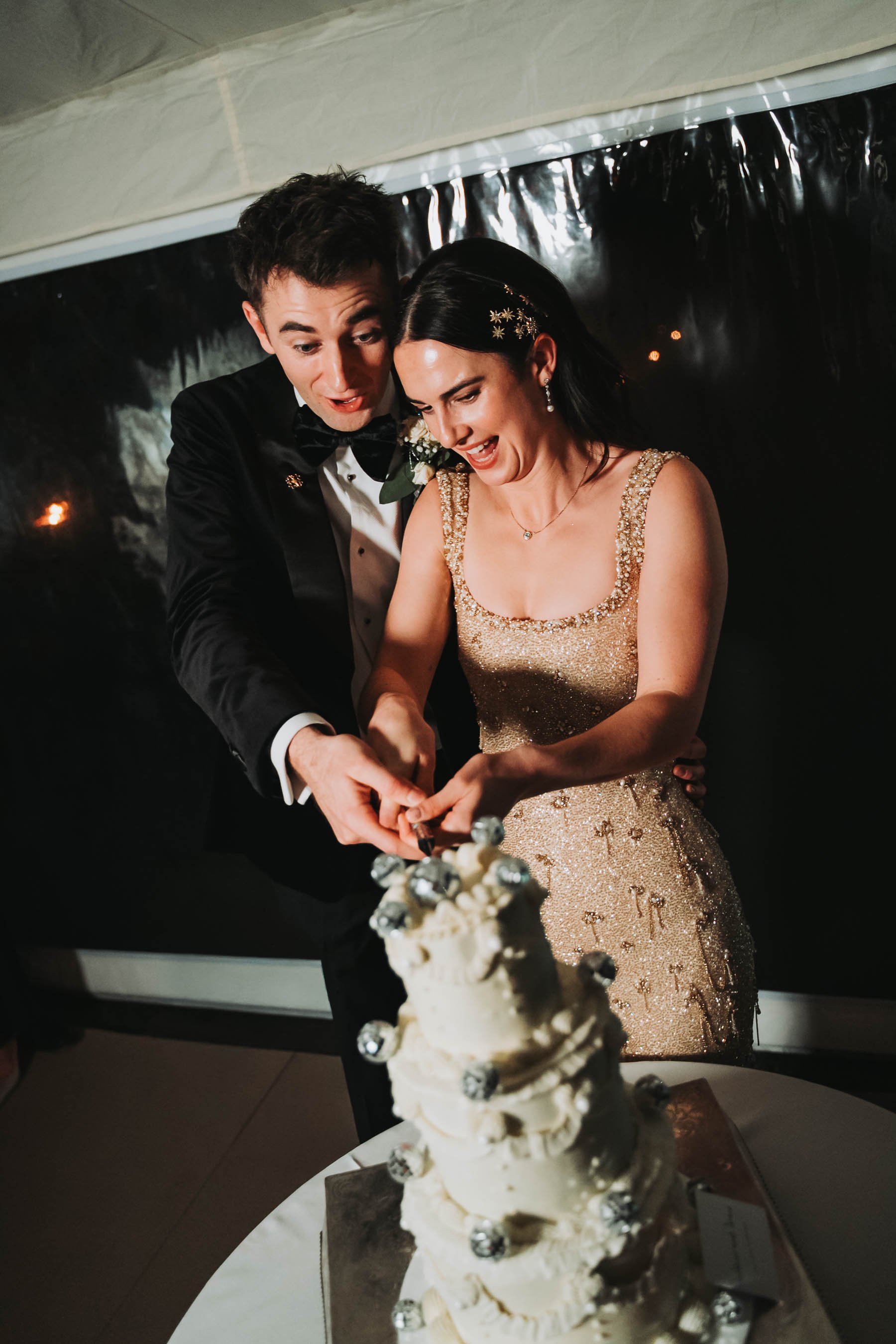 A bride and groom cut into a wedding cake together at their wedding reception.