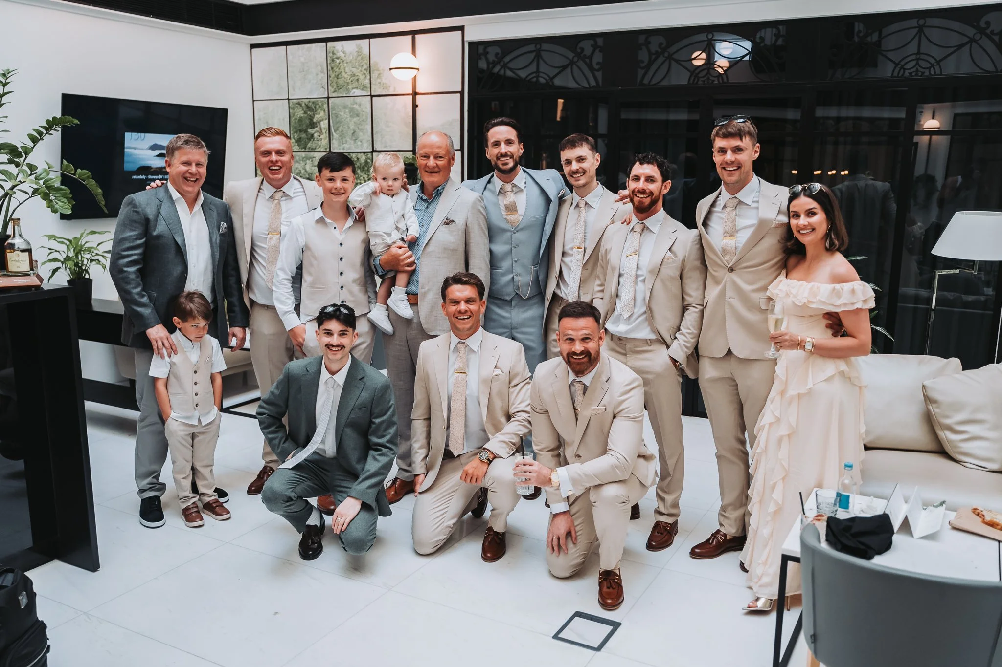 Group of people dressed in formal attire, smiling and posing indoors during a celebration or event.