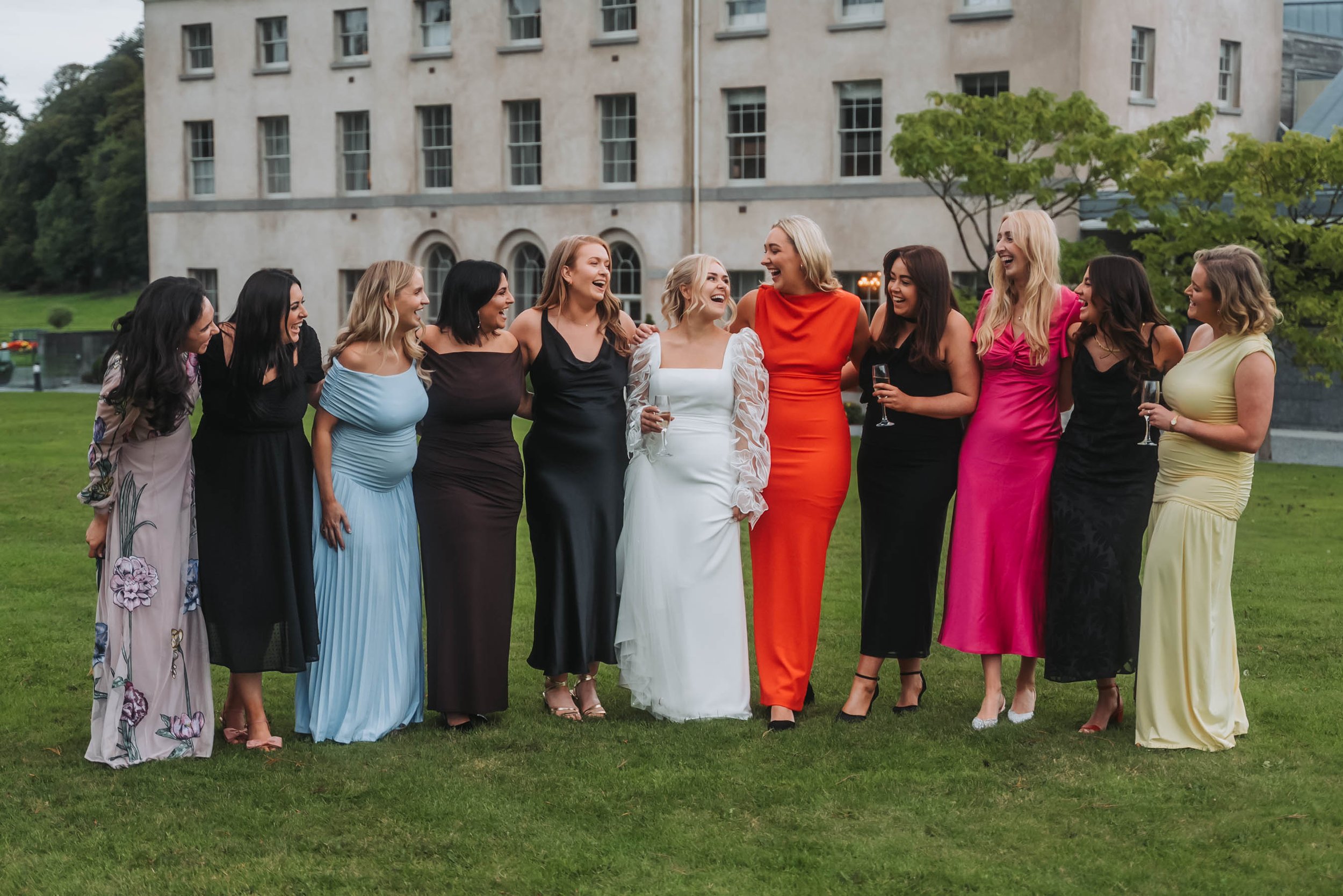 A group of women in colorful dresses standing outdoors, smiling and laughing.