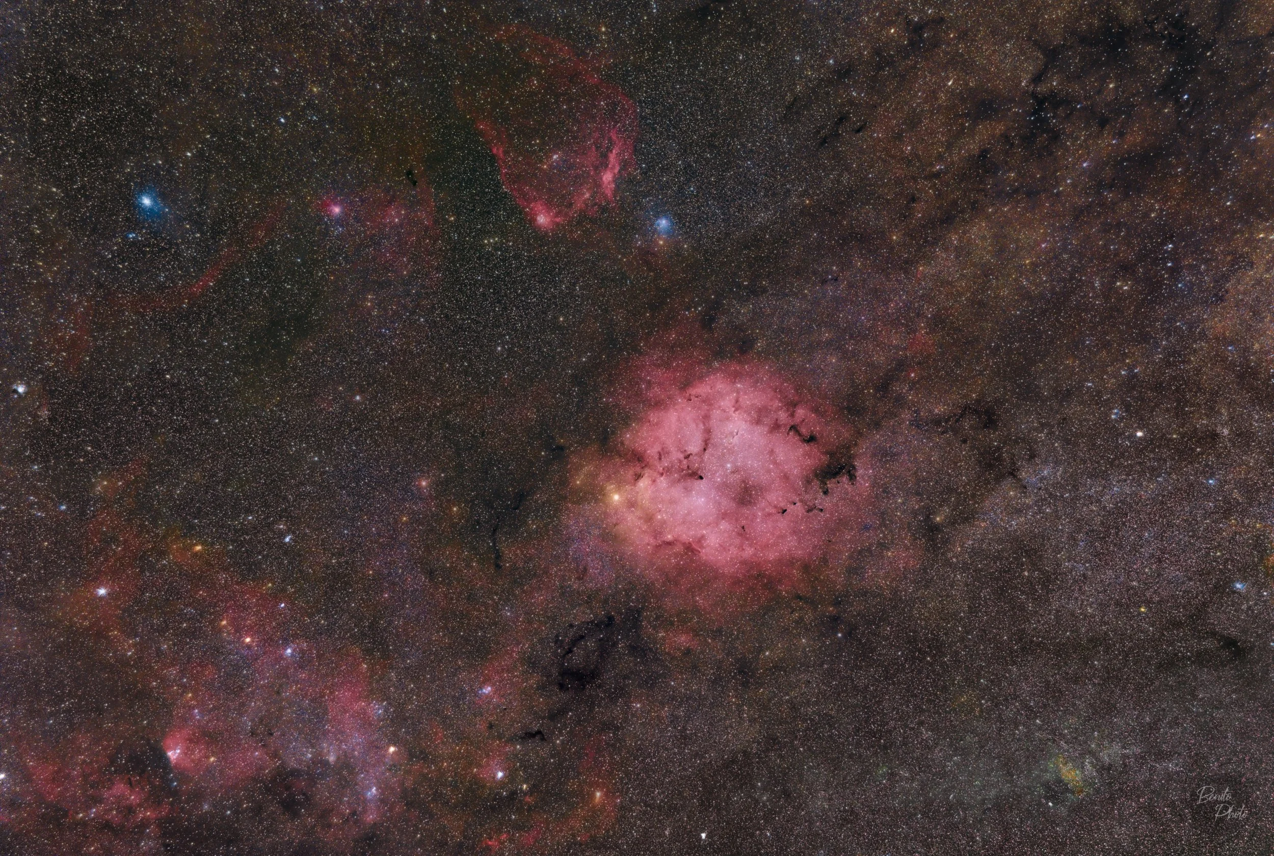 Une image de l'espace présentant une galaxie, des nébuleuses roses et de nombreuses étoiles.