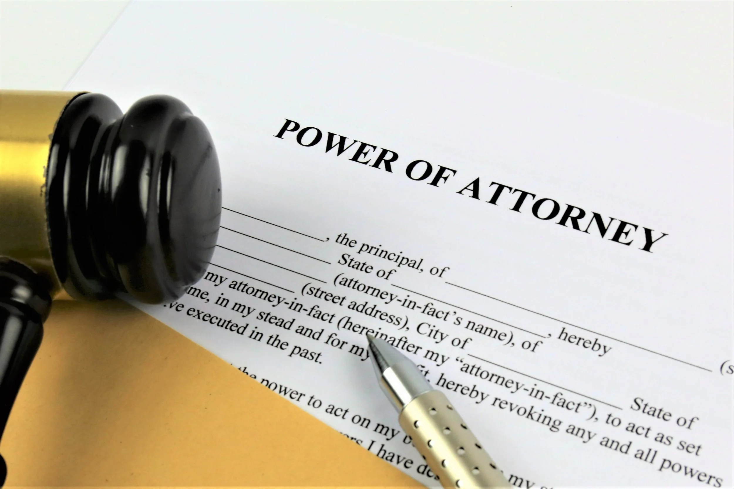 A legal document titled 'Power of Attorney' on a desk, with a black and white pen and a black rubber stamp nearby.