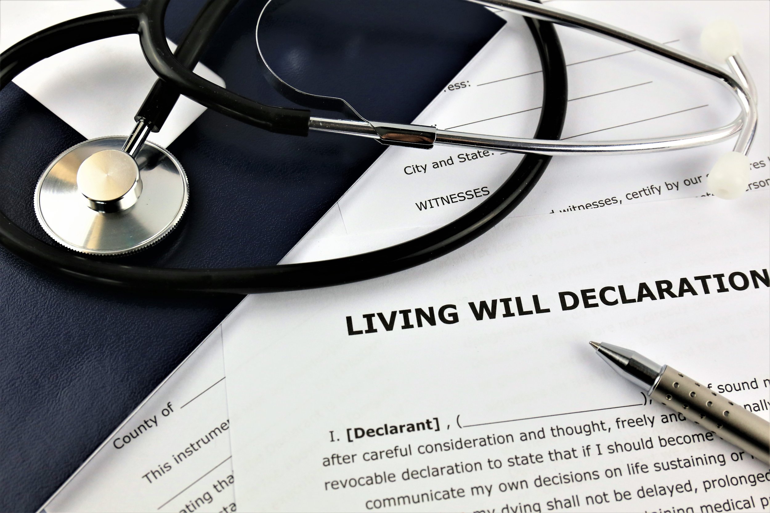 A stethoscope placed on top of a legal document titled 'Living Will Declaration' with a pen beside it.