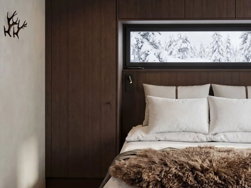 Master bedroom with a fur throw and a window framing the snowy forest.