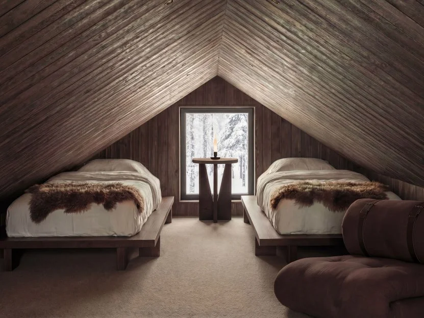 Loft bedroom with twin beds under a pitched timber ceiling.