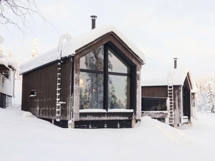 Snow-covered villa exterior with large gable window on a bright winter day.