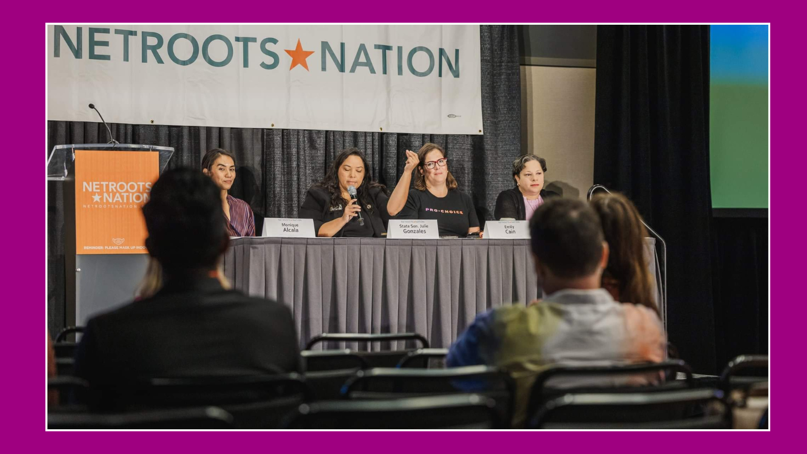 Panel of four women speaking and listening at a conference with a large 'NETROOTS NATION' banner behind them; audience seated in front.