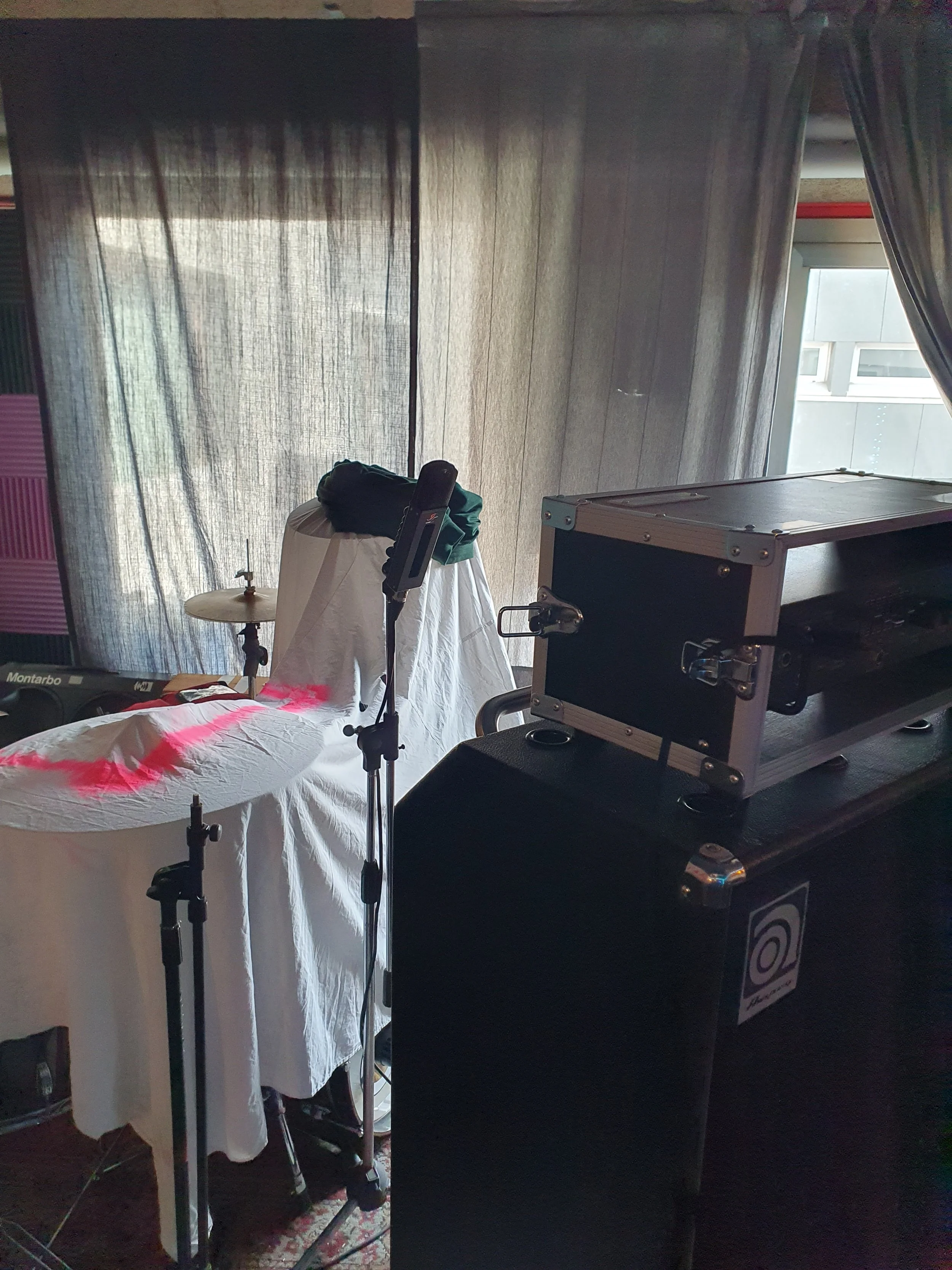 Interno di uno studio di registrazione musicale con strumenti e attrezzature come batteria, computer e casse audio.