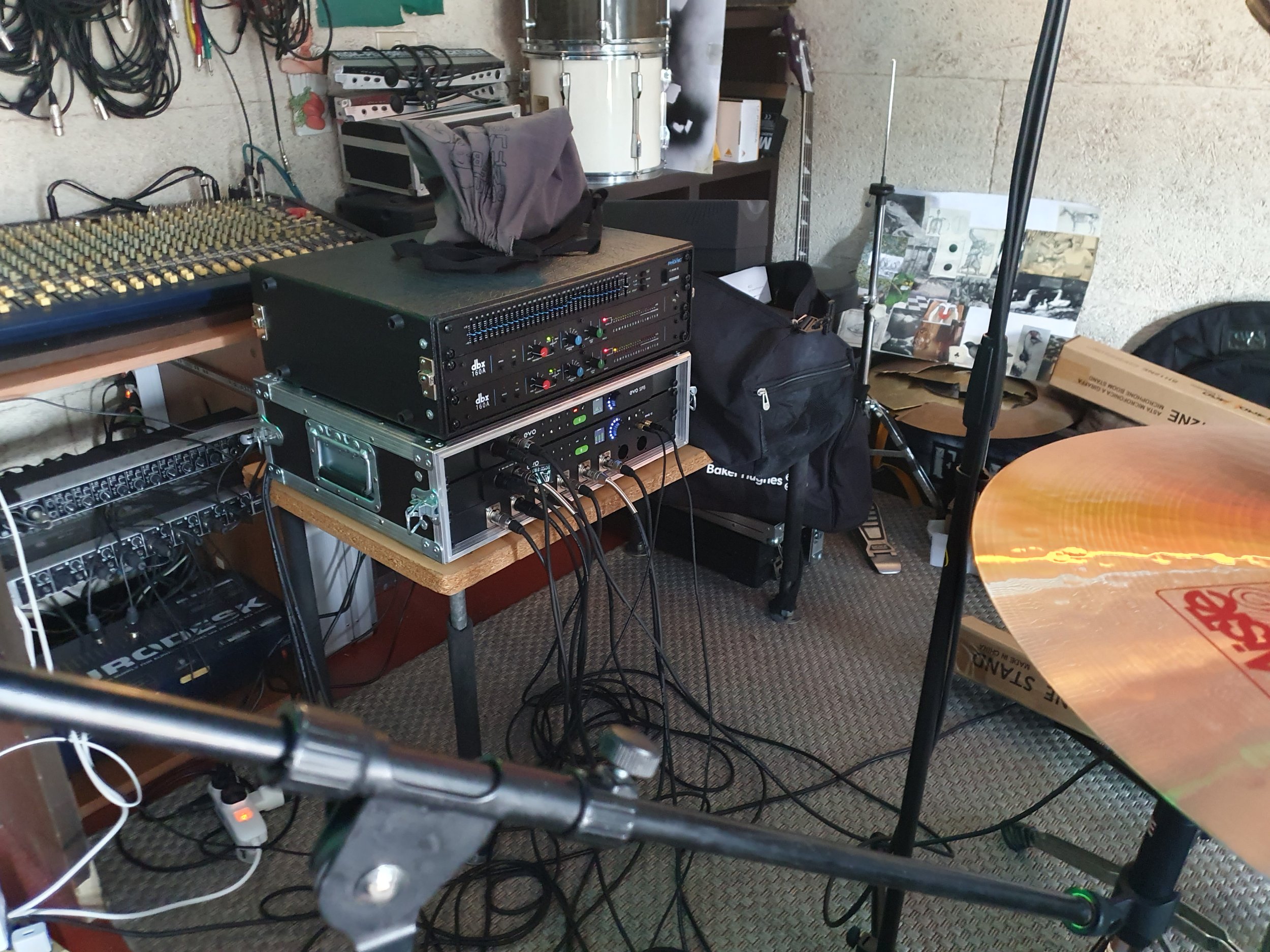Incrocio di apparecchiature audio e musicali, inclusi mixer, amplificatori e strumenti musicali in uno spazio di produttività o prova.