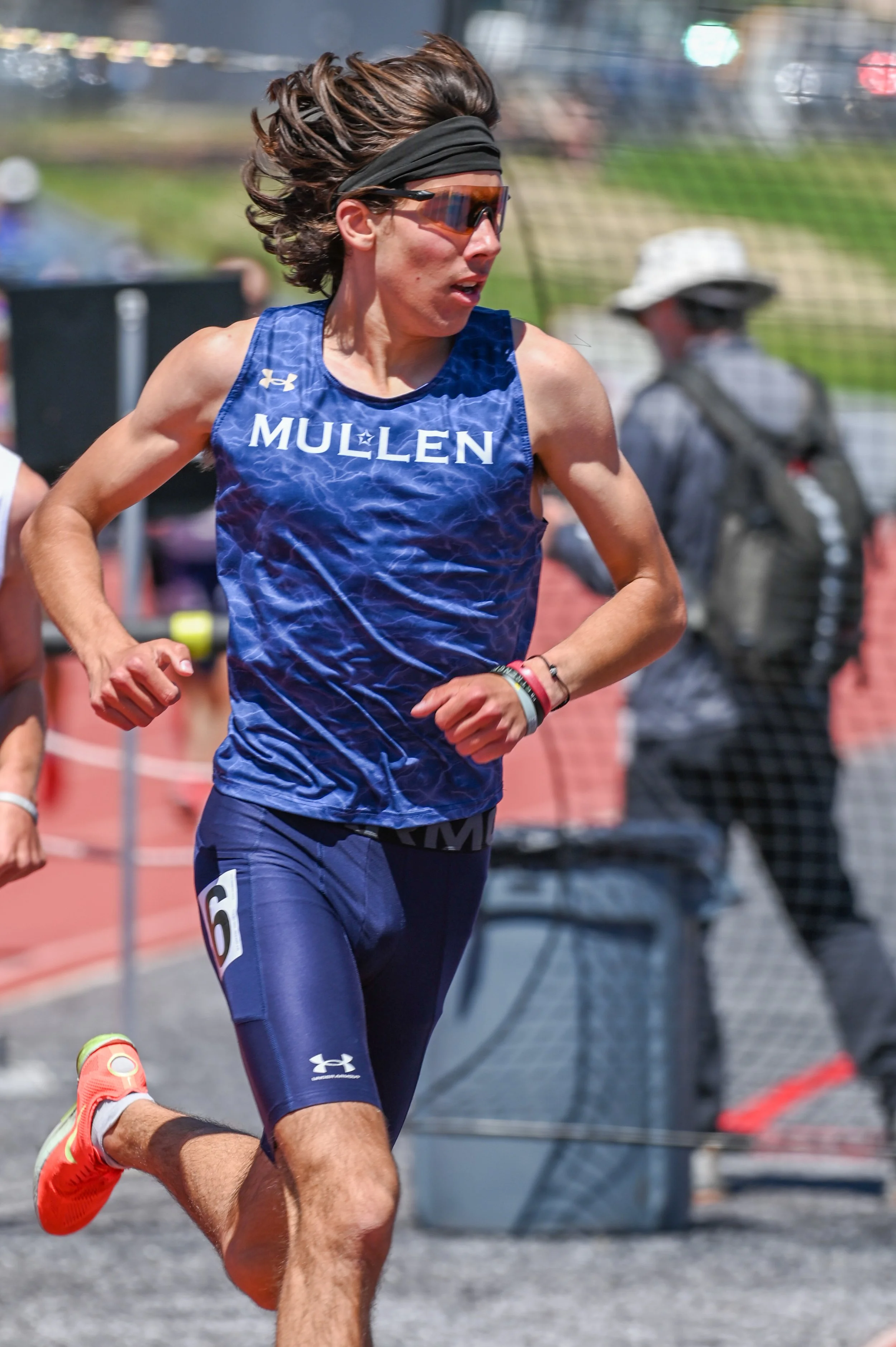 Close-up of a male runner wearing sunglasses and a blue athletic shirt with 'MULLEN' printed on it, competing in a race. 