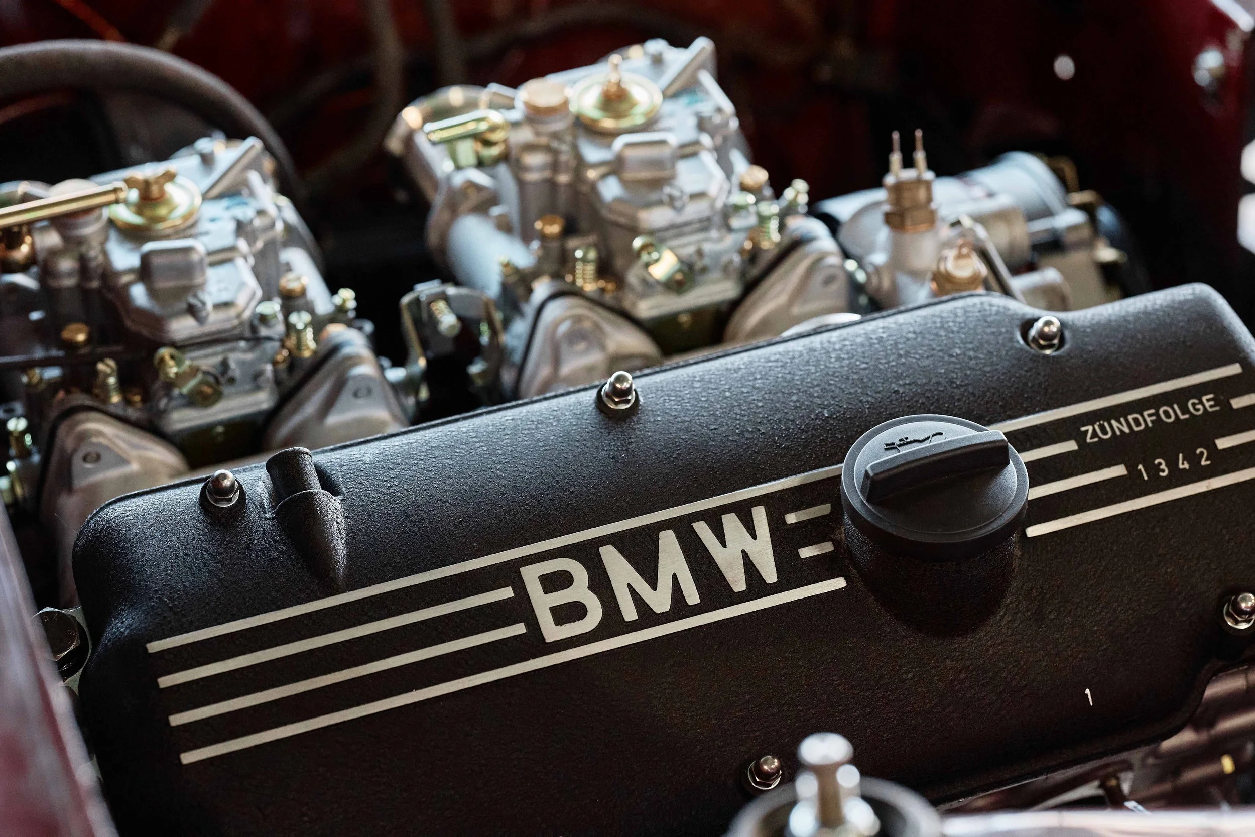 Nahaufnahme eines Motorblocks eines BMW-Motors mit sichtbaren Vergasern und Zündfolge