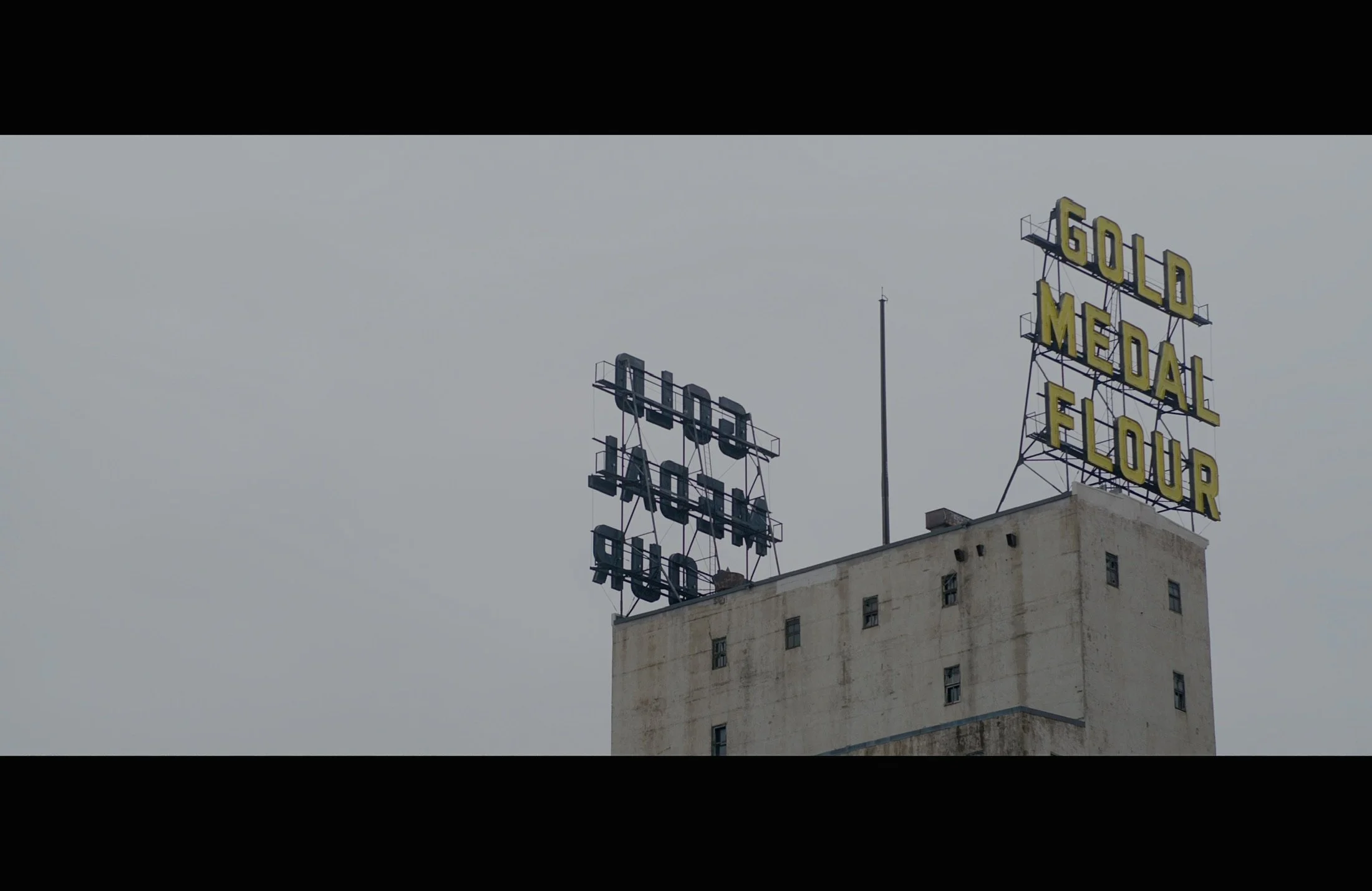 View of the rooftop signs on a building with the words 'GOLD MEDAL FLOUR' in yellow letters on a black metal framework.