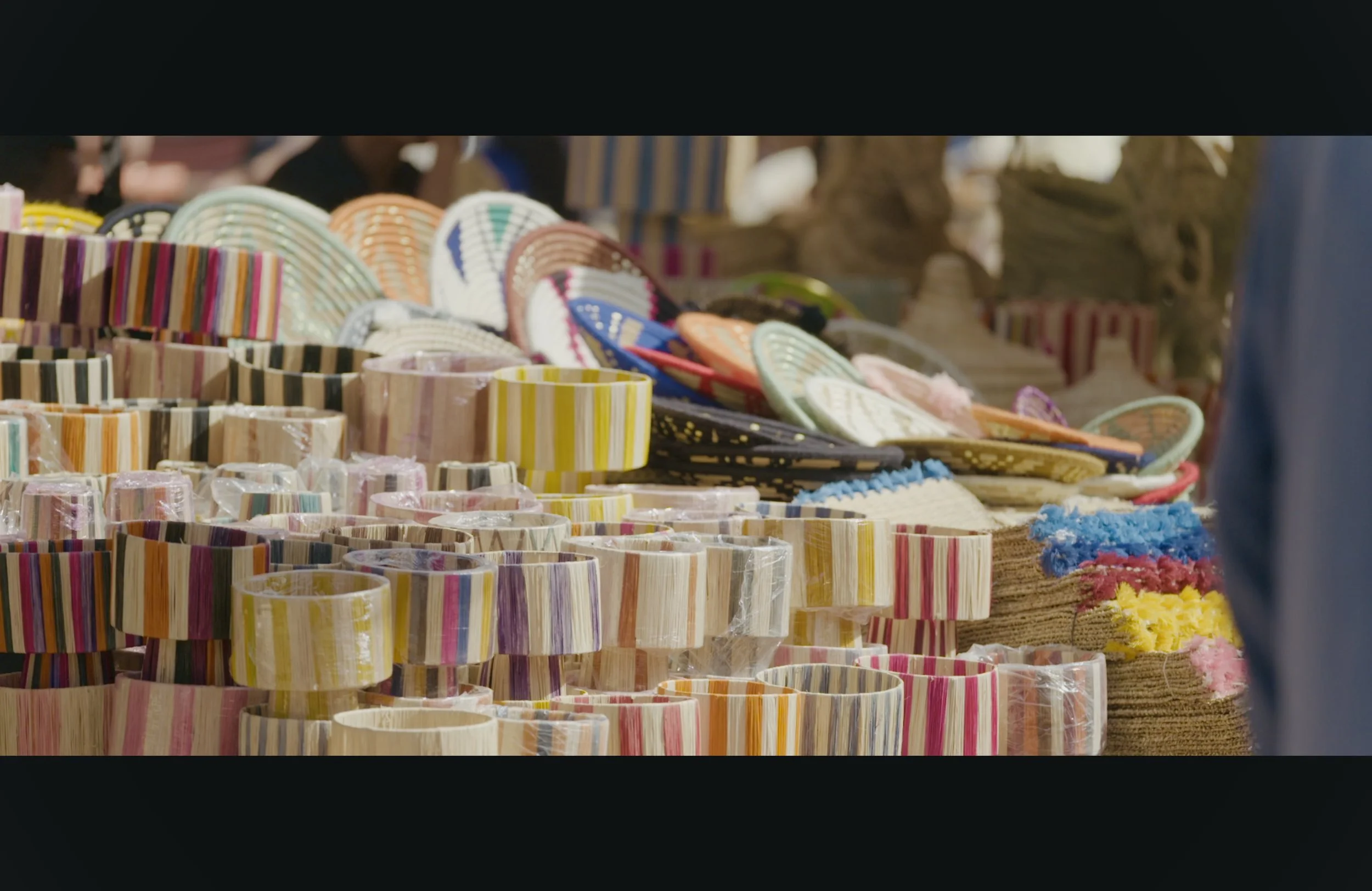 Colorful woven baskets and bowls displayed on market stalls at an outdoor market.