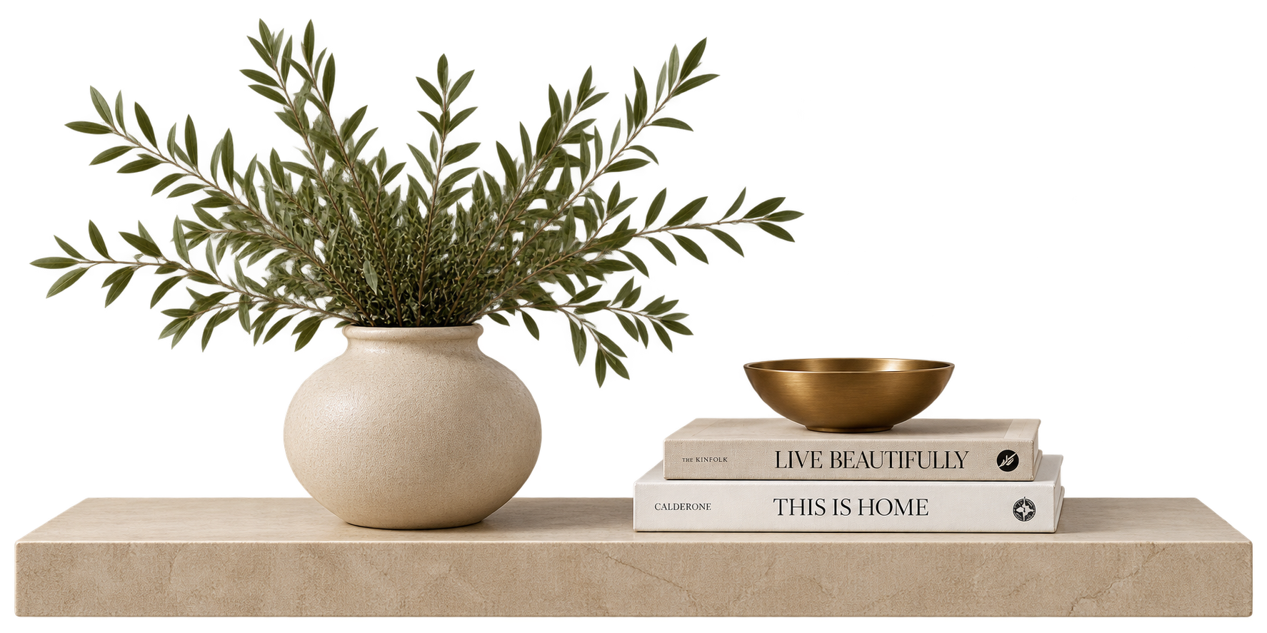 Decorative arrangement of a large potted green plant with elongated leaves, a stack of two neutral-toned books titled 'Live Beautifully' and 'This Is Home,' a small gold-colored bowl, all placed on a beige stone surface.