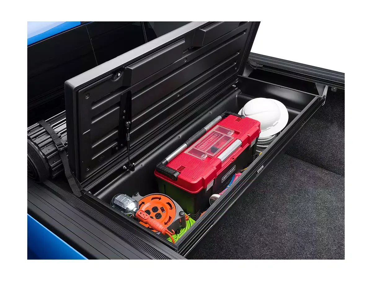 Open compartment of a vehicle trunk containing a red toolbox, a white helmet, an orange extension cord, and various tools and equipment.