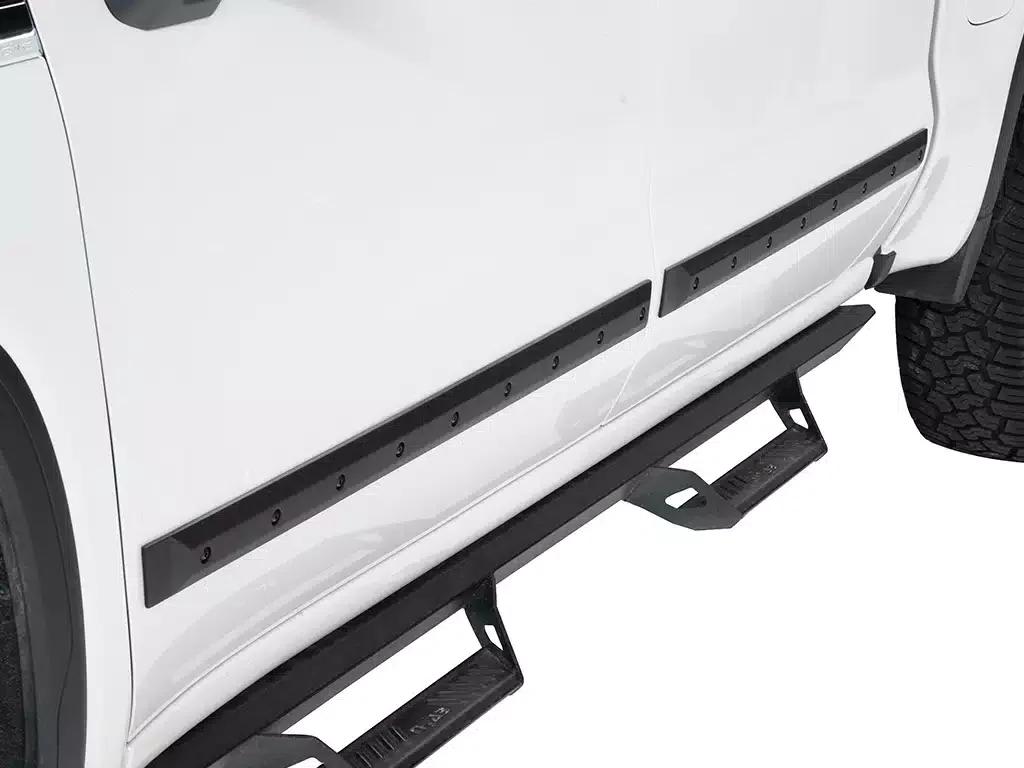 Side view of a white vehicle with black side steps and black side rail protectors.