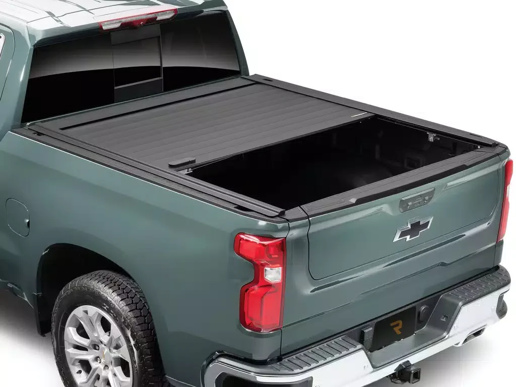 Green pickup truck with the tailgate open, showing the bed and a tonneau cover. The Chevrolet logo is on the tailgate.