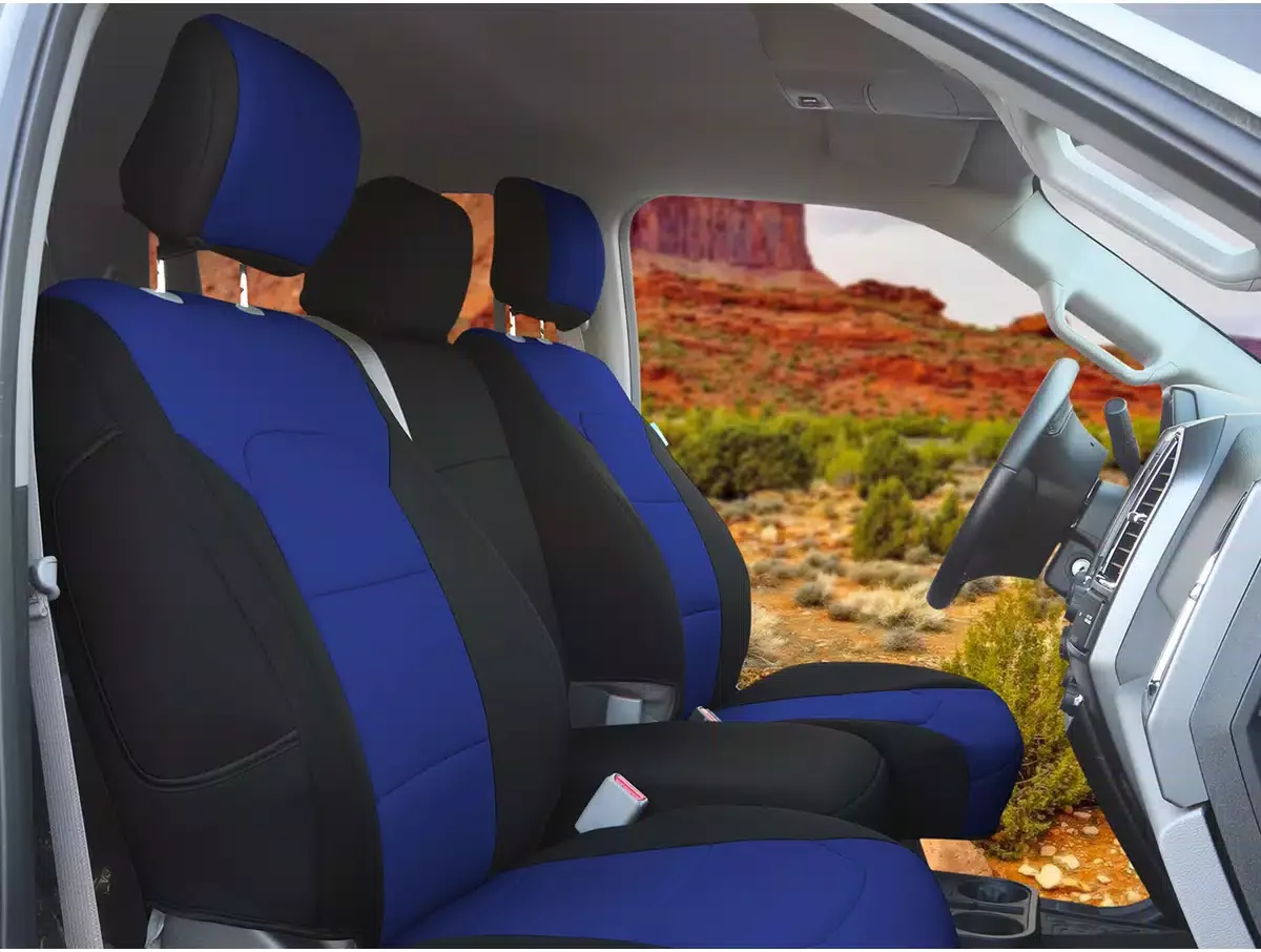 Interior of a vehicle with blue and black seats, outside view of desert landscape with red rock formations and sparse vegetation.